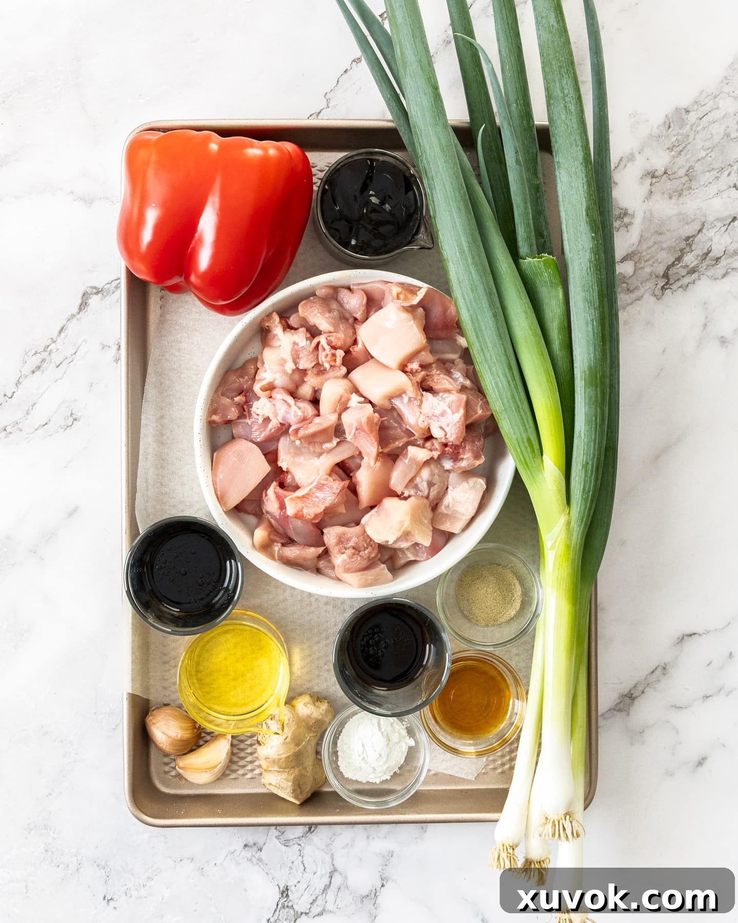 Fresh ingredients for chicken in oyster sauce, neatly arranged on a baking tray.