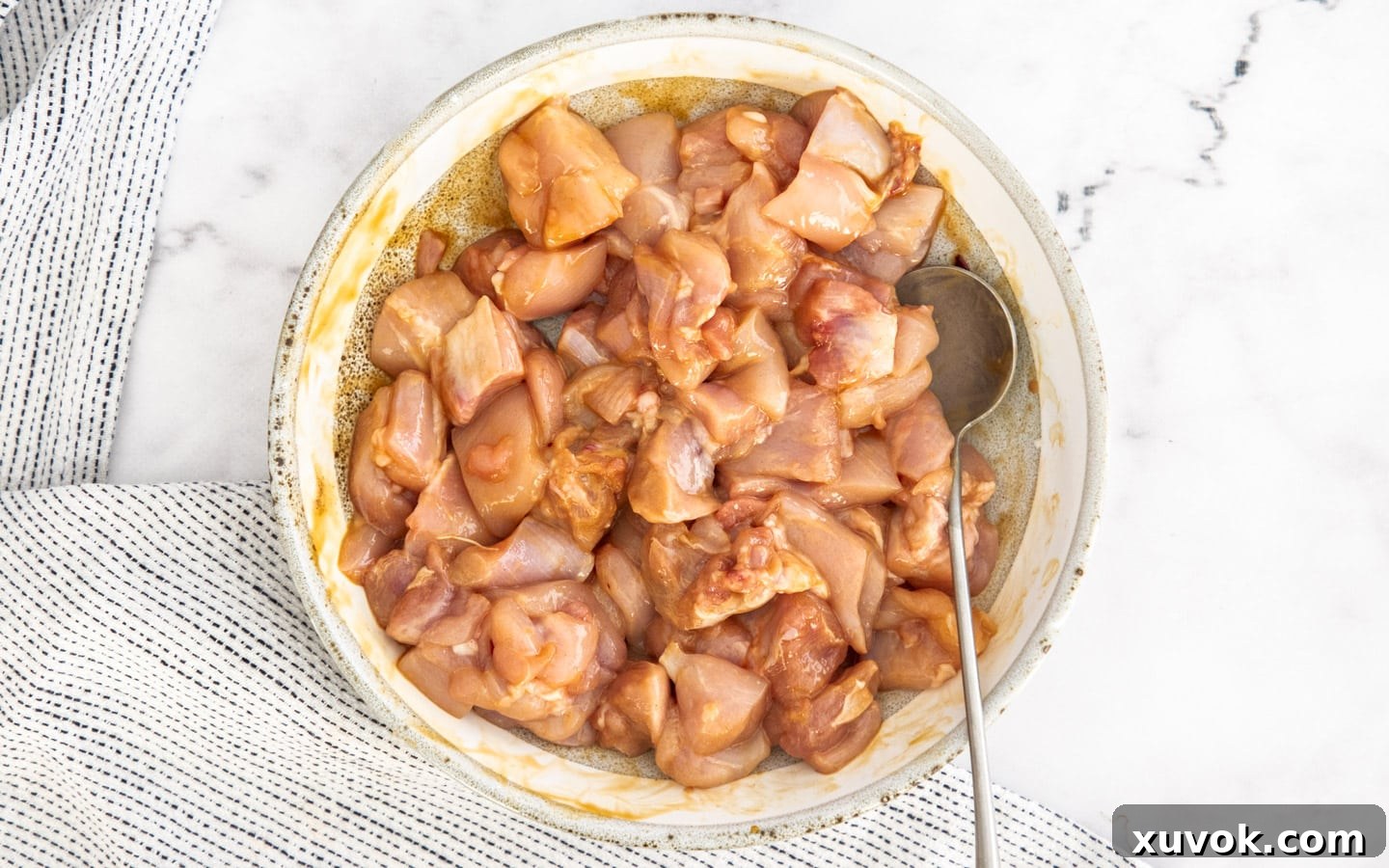 Bite-sized chicken pieces mixed with seasoning in a bowl.