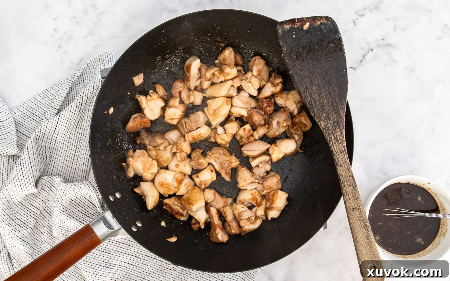 Chicken pieces searing in a hot wok, developing a golden crust.