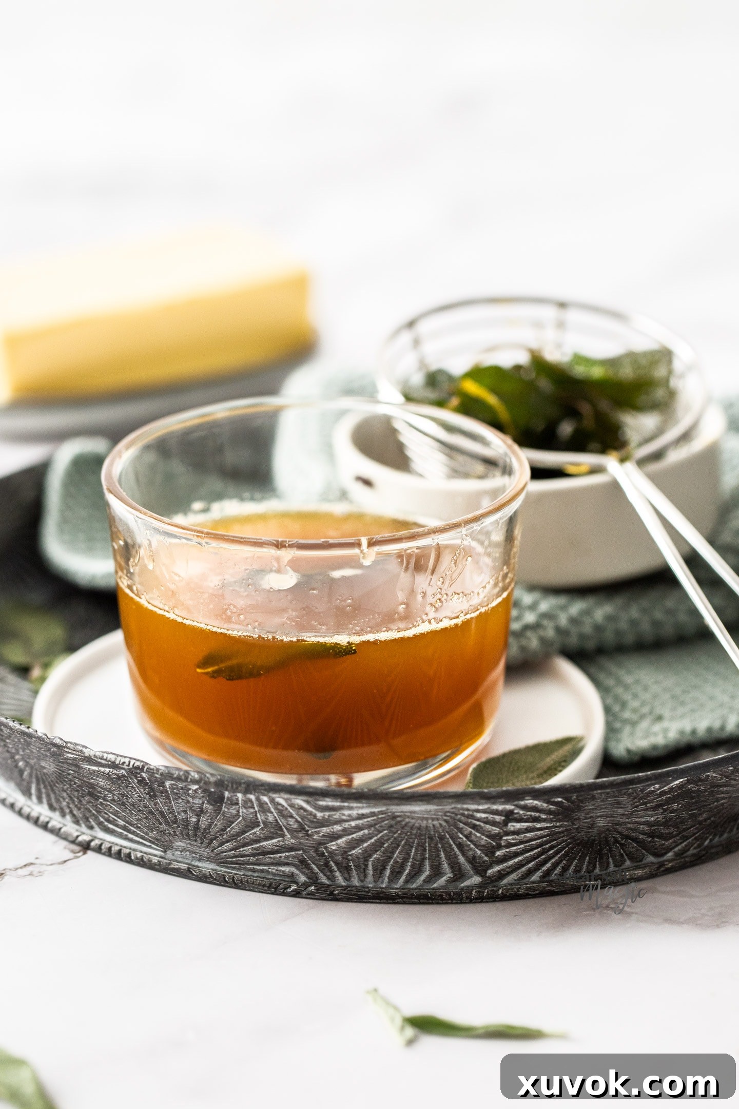 A glass with amber brown butter sage sauce inside.