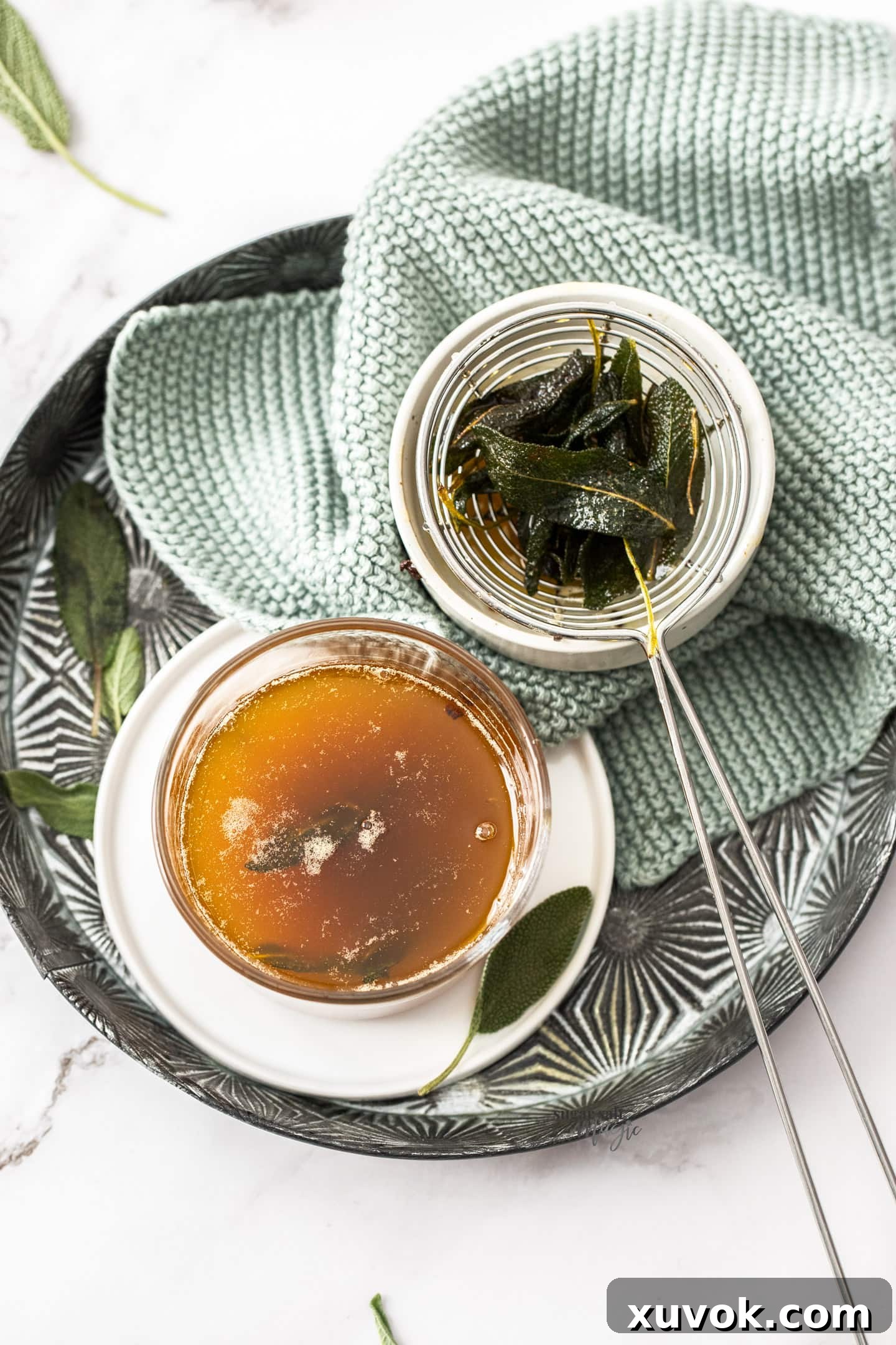 A glass of sage butter sauce with some crispy sage on the side, ready to be served.