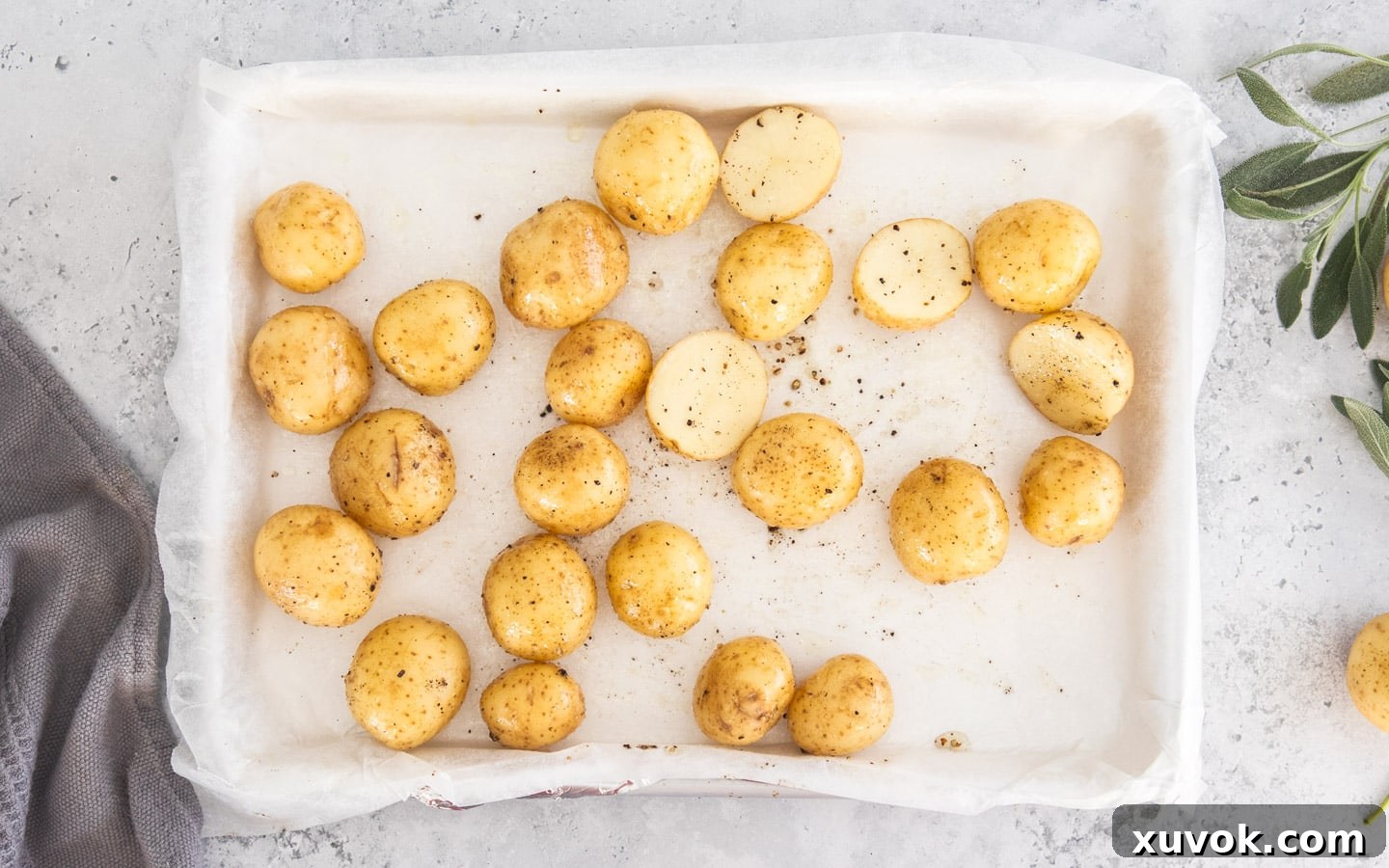 Baby potatoes seasoned with salt and pepper on a baking tray.