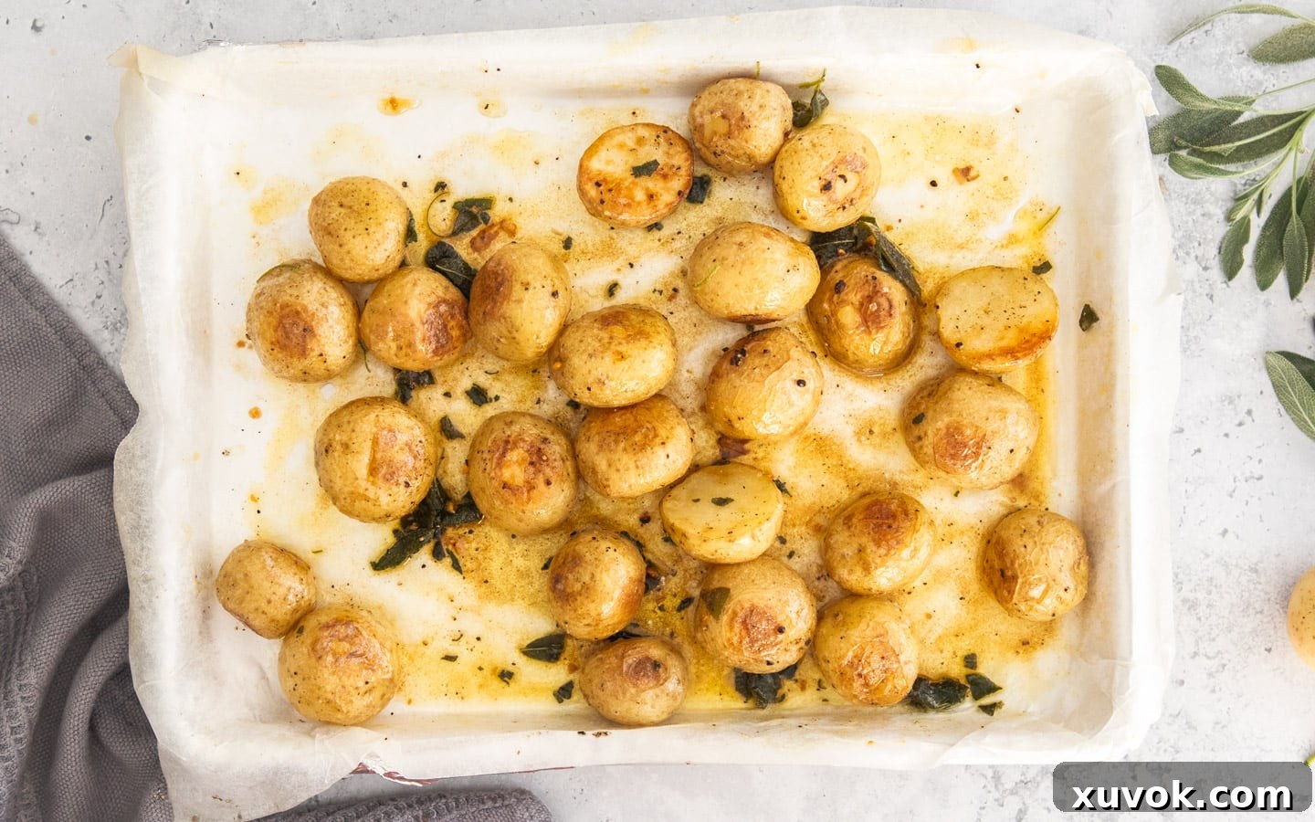 The roasted potatoes dressed with sage browned butter on a baking sheet.