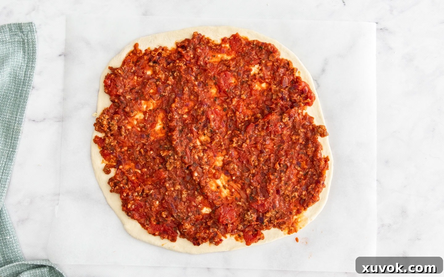 The tomato meat sauce spread on the pizza base.