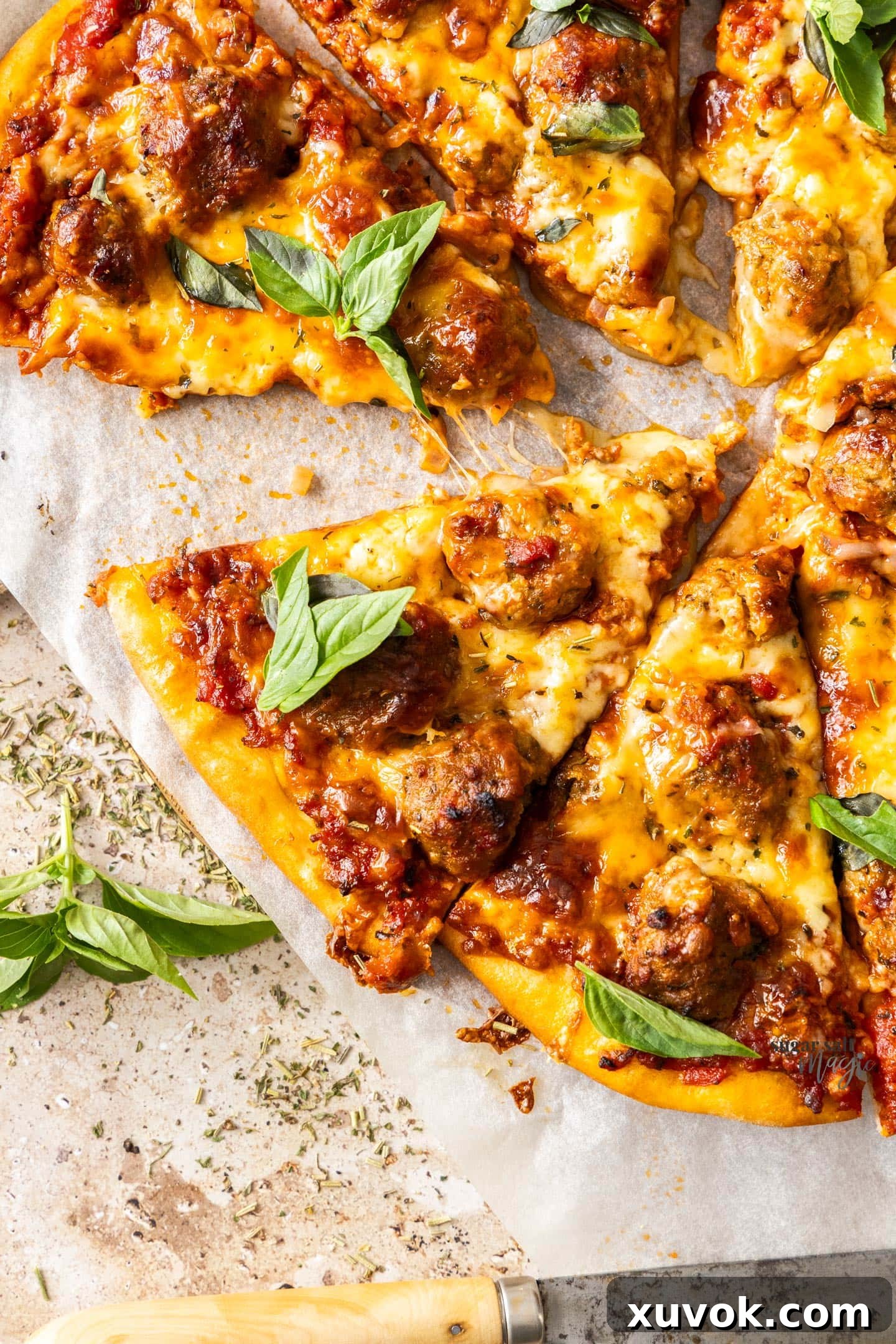 Slices of meatball pizza on a sheet of baking paper.