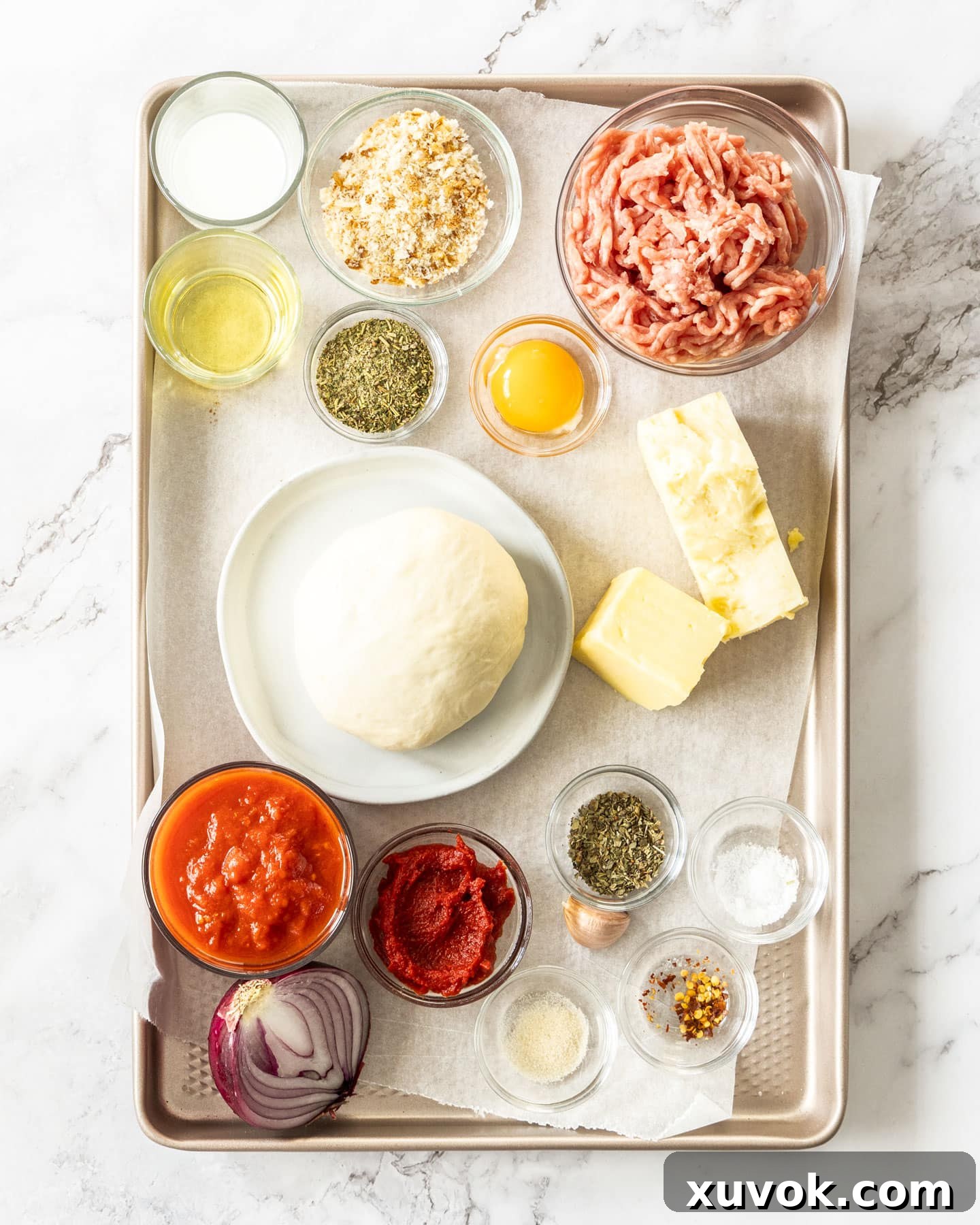 Ingredients for meatball pizza on a baking tray.