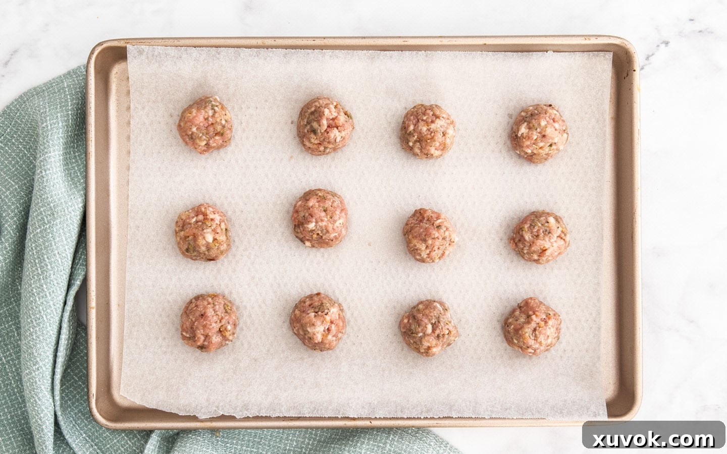 Balls of the meat mixture rolled on a baking tray.