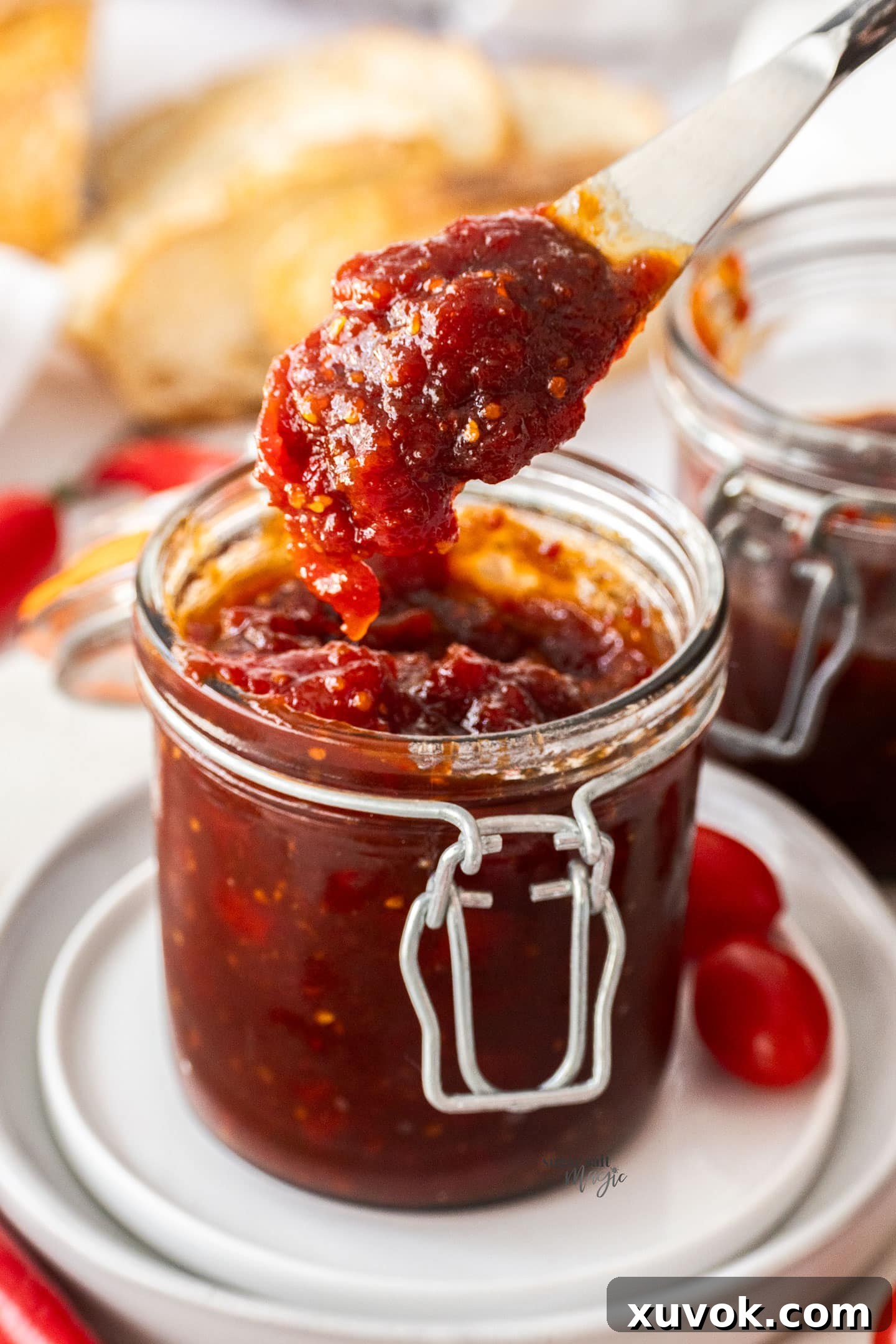 A knife scooping jam from a jar.