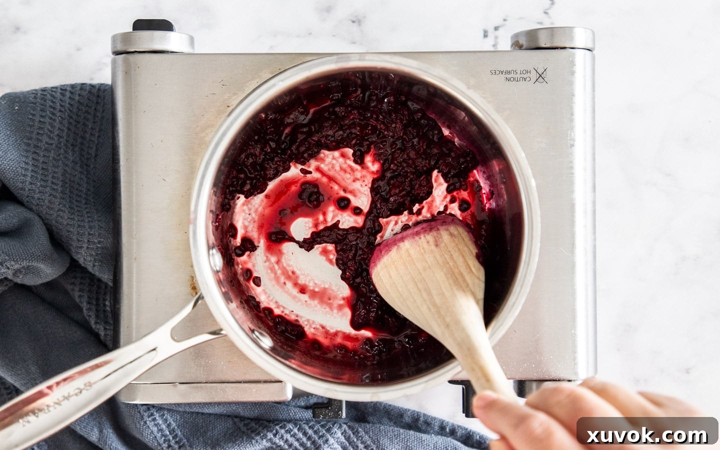 Blackberries, sugar, and water simmering in a small saucepan, creating a homemade compote.