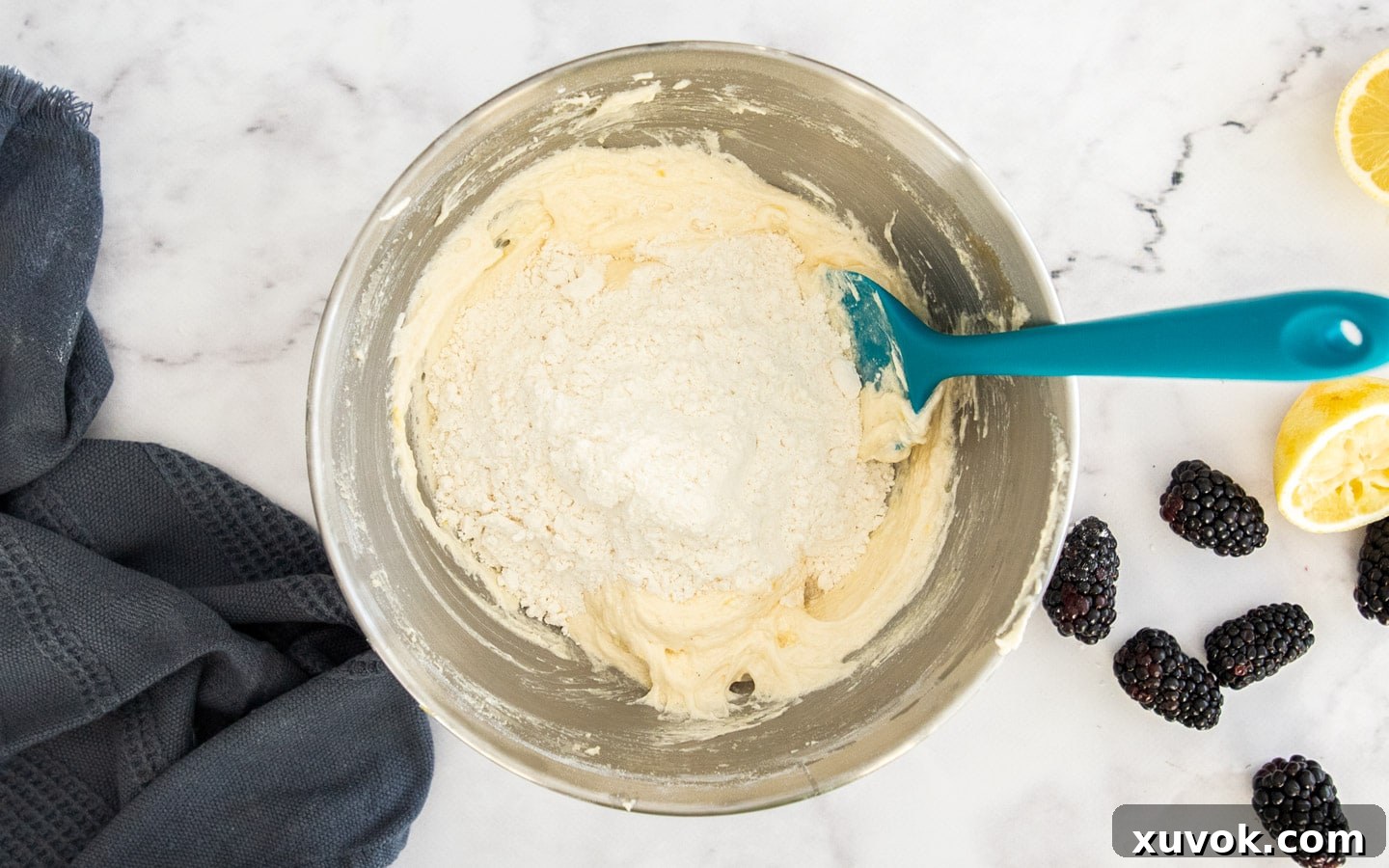 The initial addition of flour mixture being gently incorporated into the creamy egg and butter base.