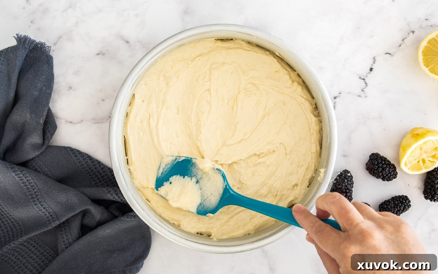 The smooth cake batter being spread evenly into a 9-inch round cake pan.