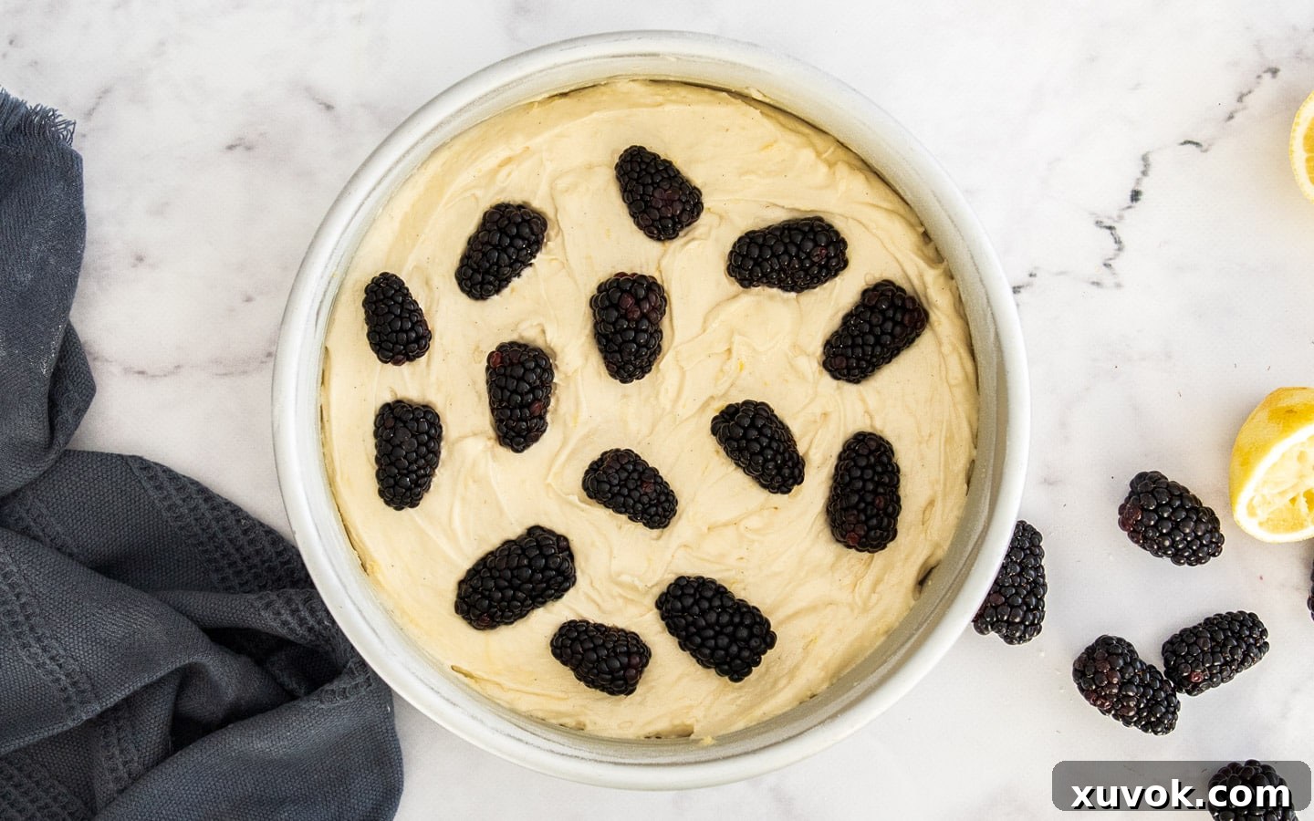 The cake batter in a pan, beautifully dotted with fresh blackberries before baking.