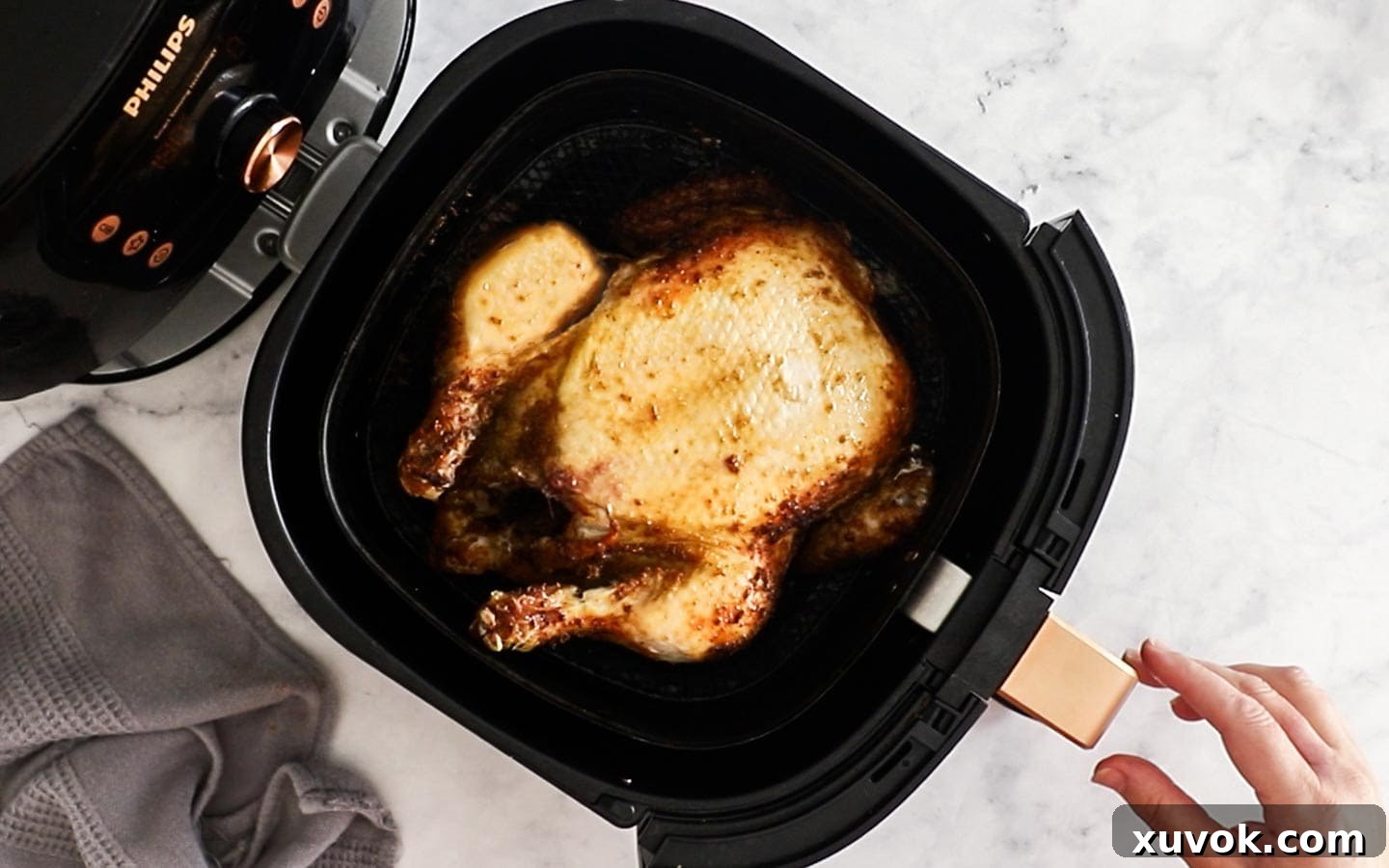 Whole chicken in the air fryer basket flipped to show the breast side.