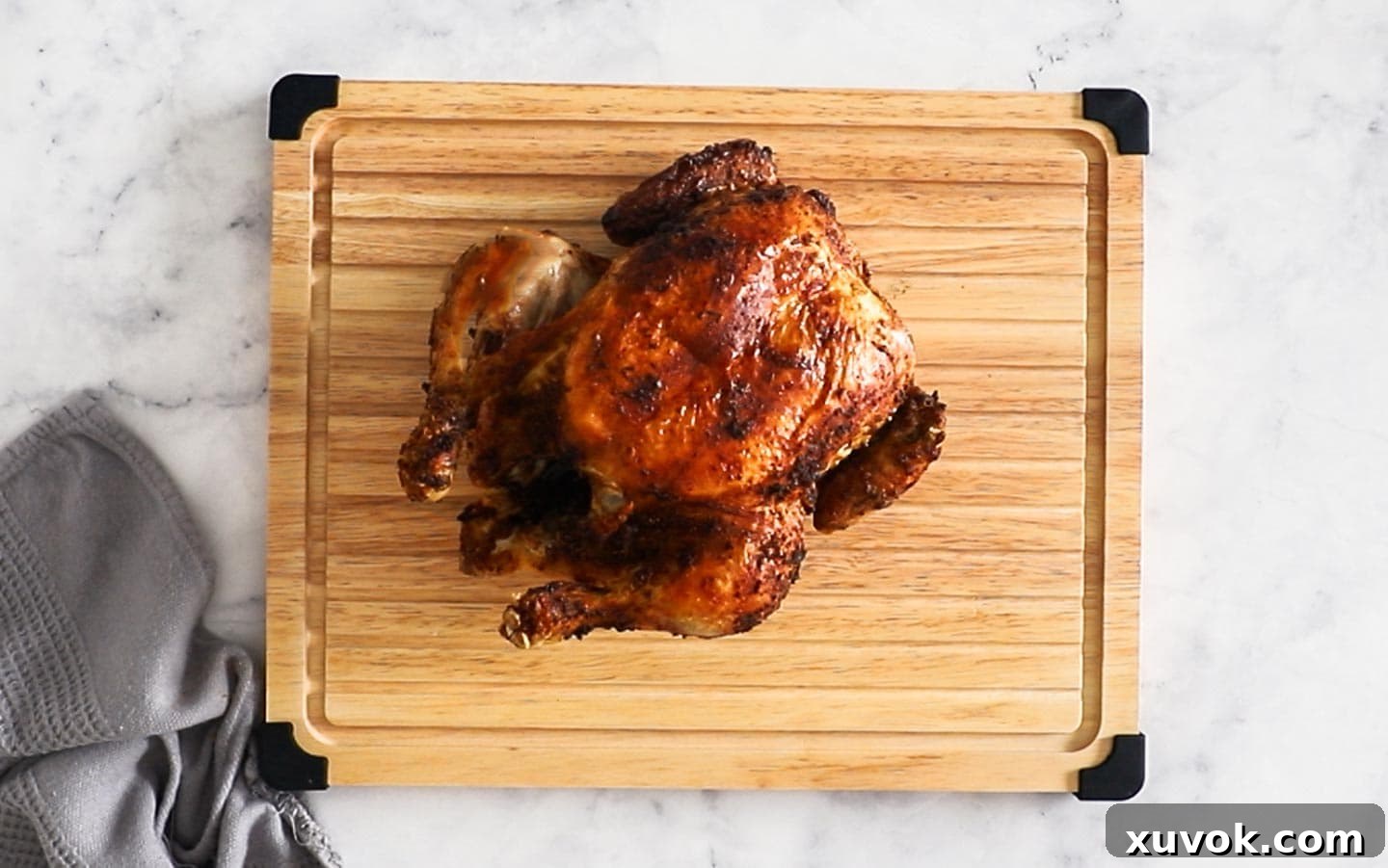 A whole air fryer chicken on a cutting board, resting.