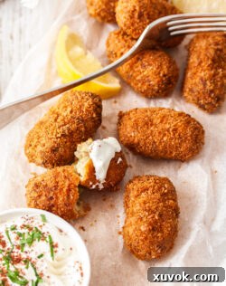 Eight perfectly fried pork croquettes on a sheet of baking paper, ready to be served.