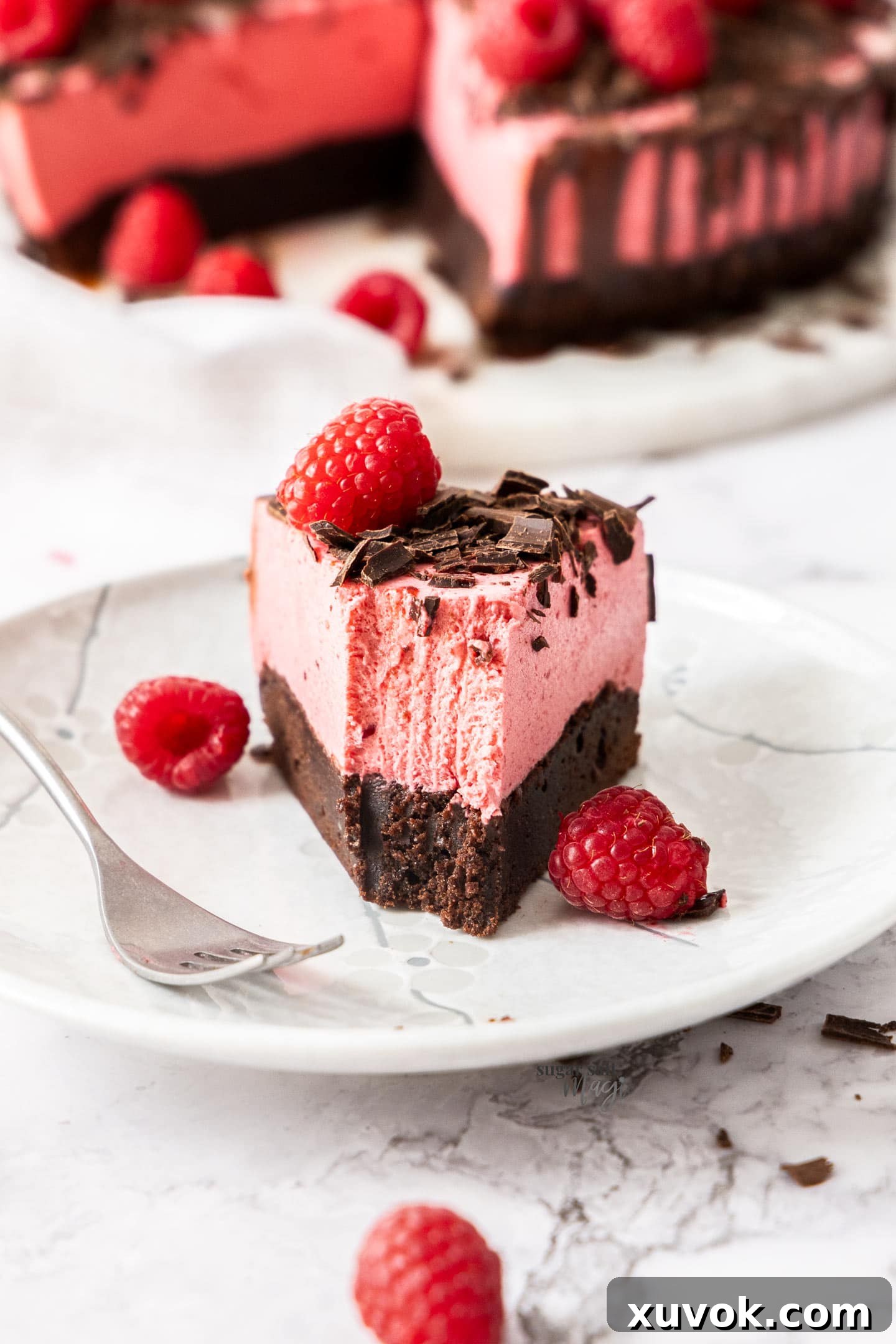 A delightful slice of mousse cake on a dessert plate with a forkful already removed, inviting indulgence.