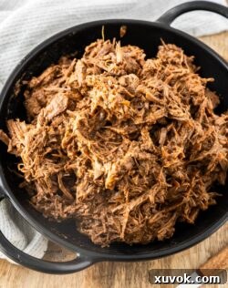 A batch of slow cooker pulled beef in a black bowl.
