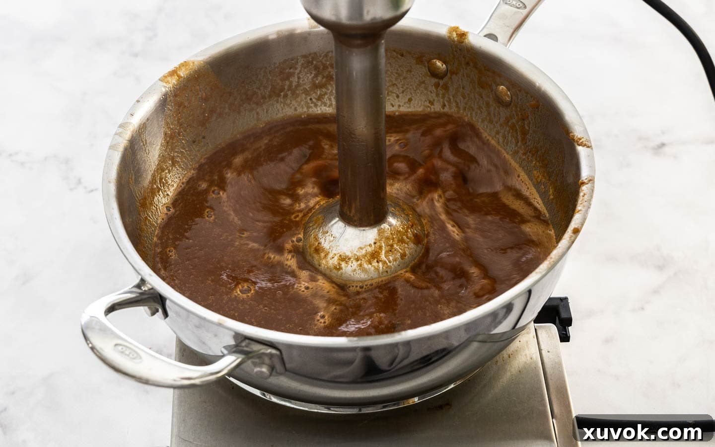 Blending the gravy to a smooth consistency with an immersion blender.