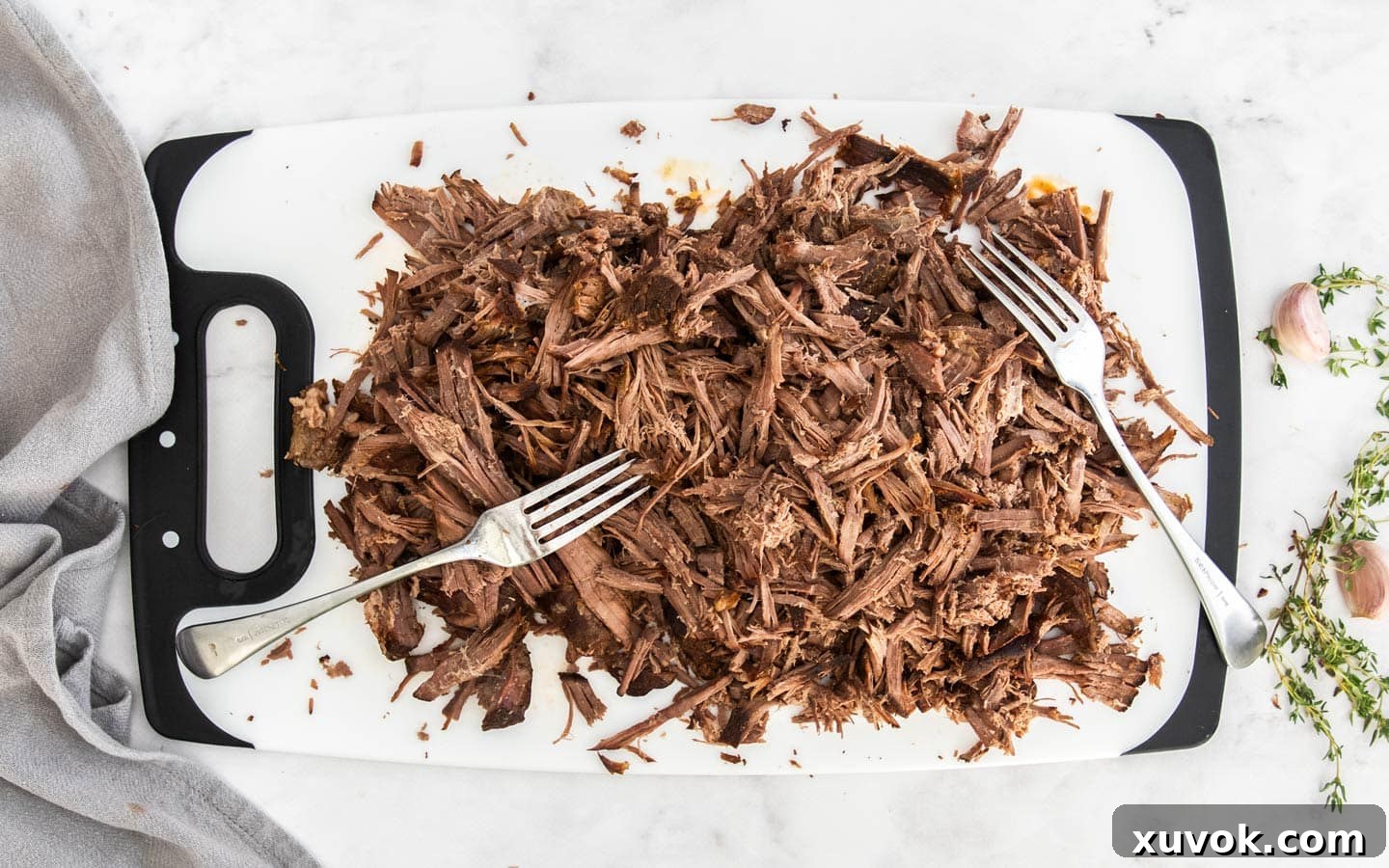 Shredded meat resting on a chopping board, ready to be combined with gravy.
