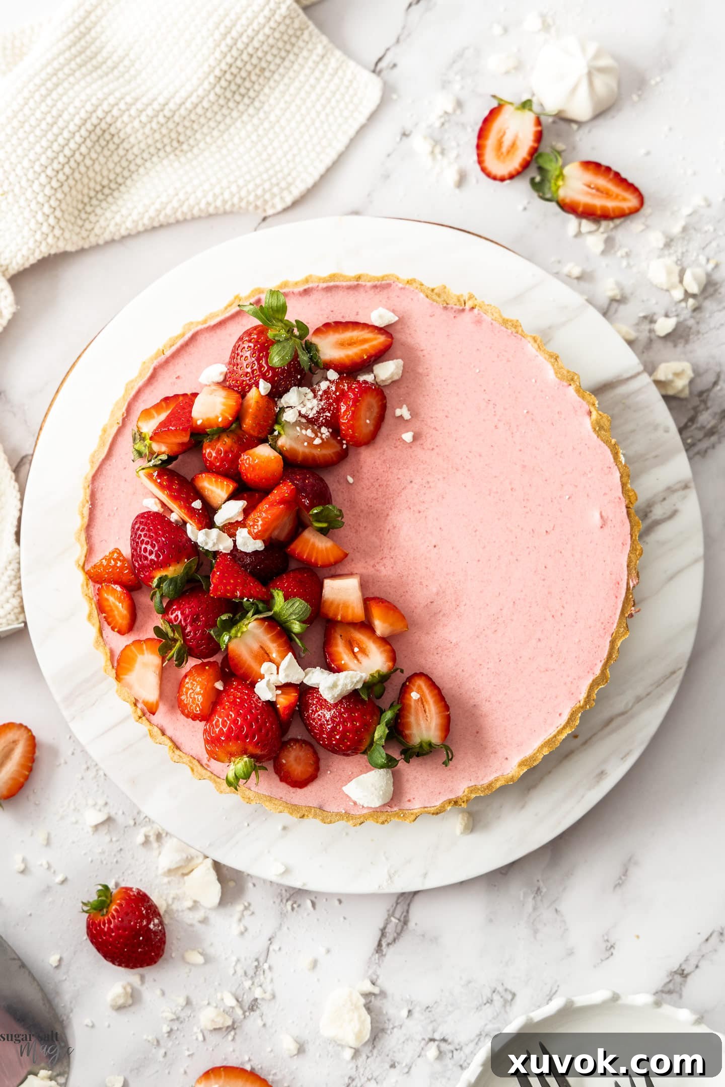 Top down view of a strawberry mousse tart on a marble platter, garnished with fresh strawberries.