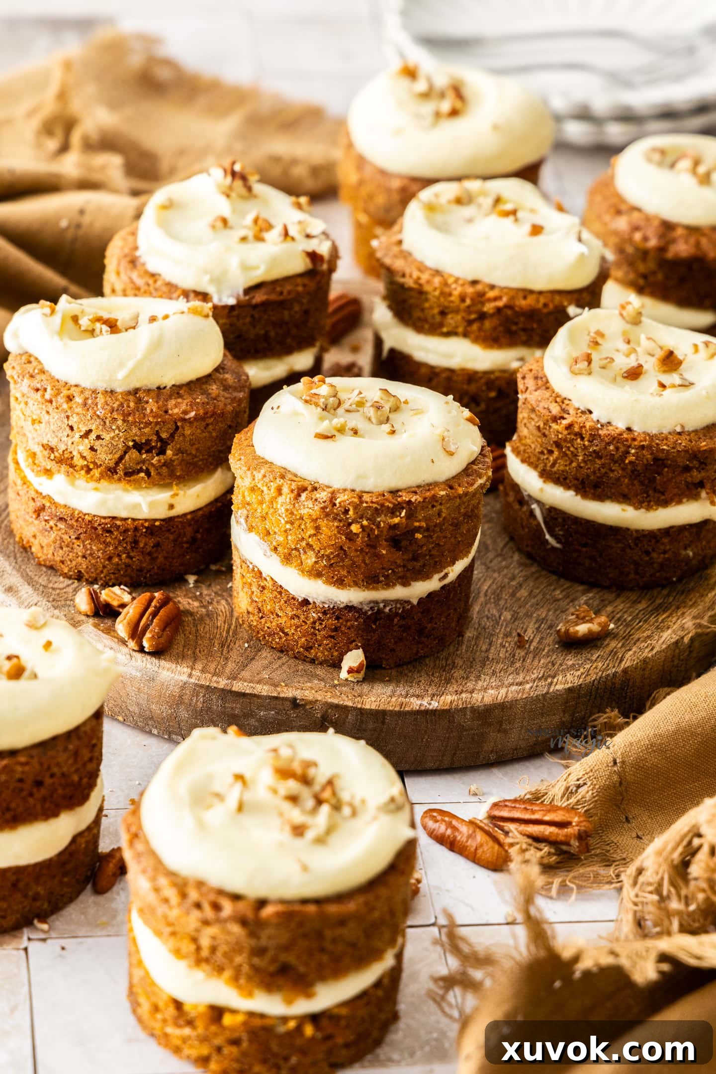A beautifully arranged batch of 9 mini carrot cakes on a rustic wooden platter, ready to be served.