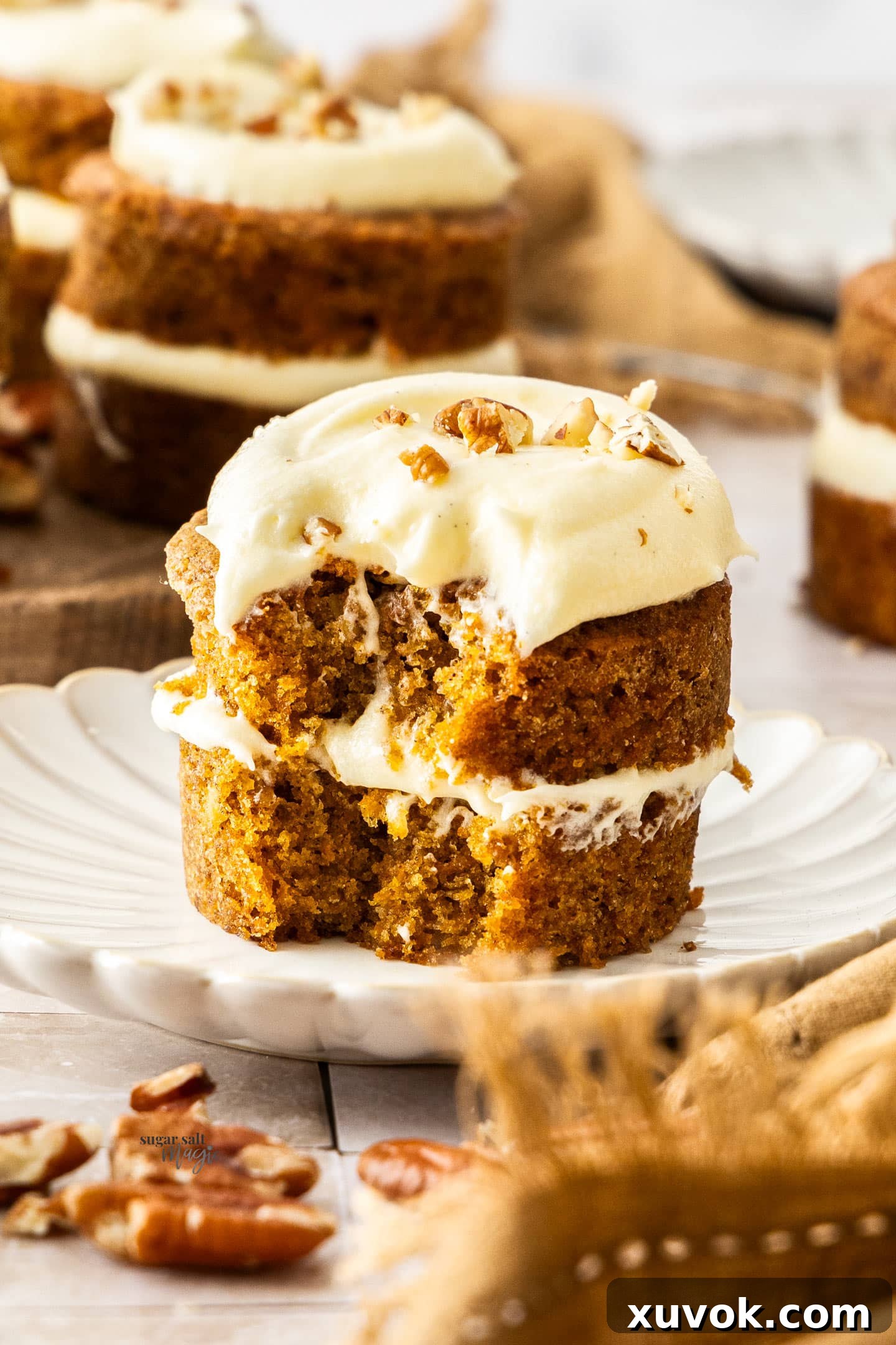 A close-up of a mini carrot cake with a forkful already cut out, revealing the moist, fluffy texture and layers of frosting.