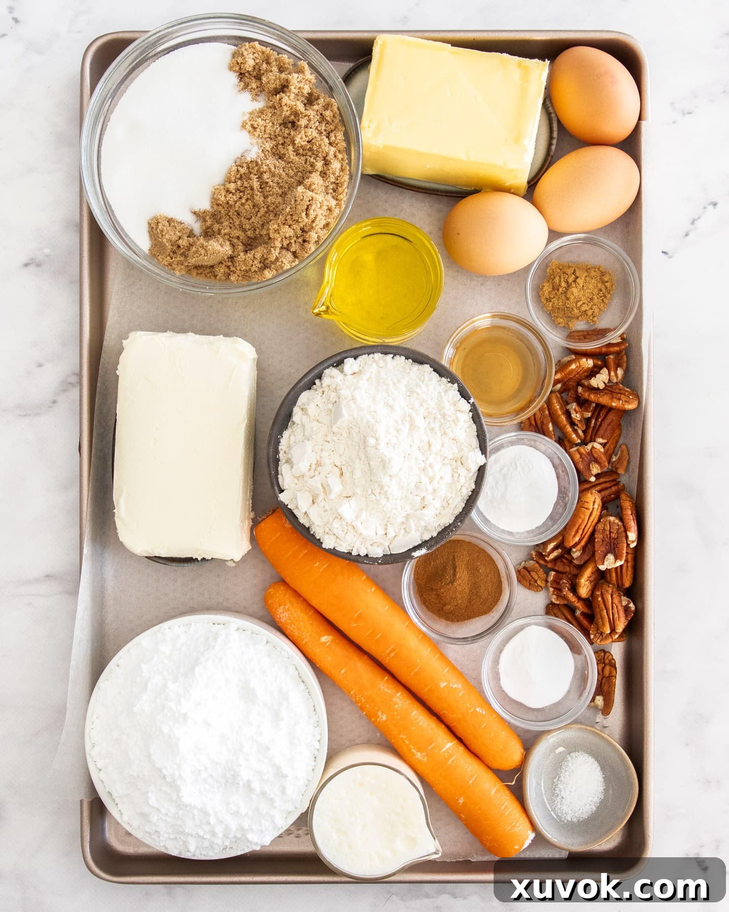 Carefully laid out ingredients for mini carrot cakes on a baking tray, highlighting fresh carrots, spices, and nuts.