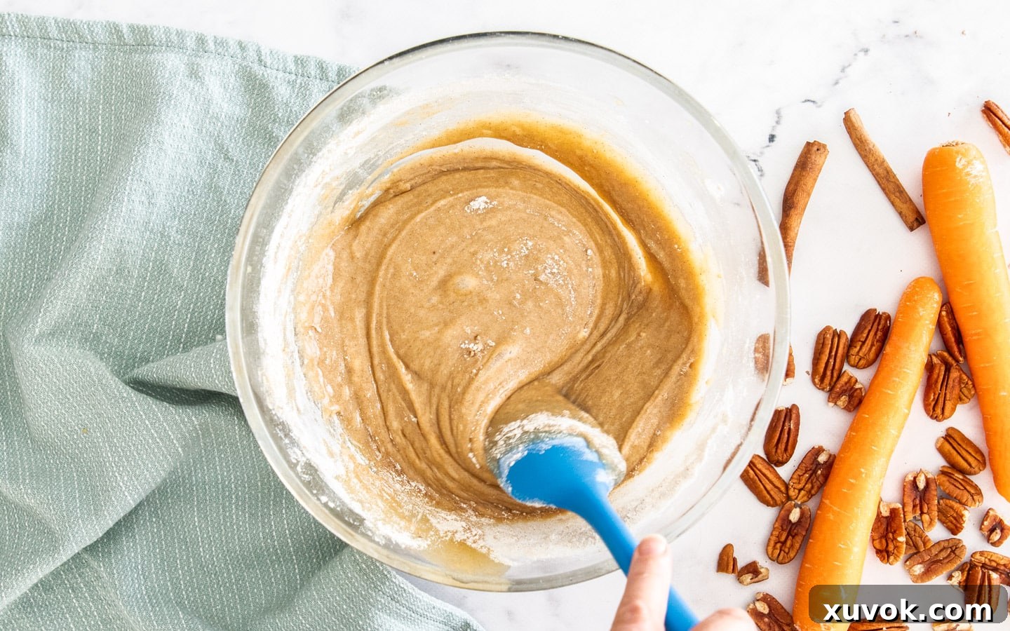 A spatula gently stirring flour into the wet batter, showing the process of combining the mixtures.