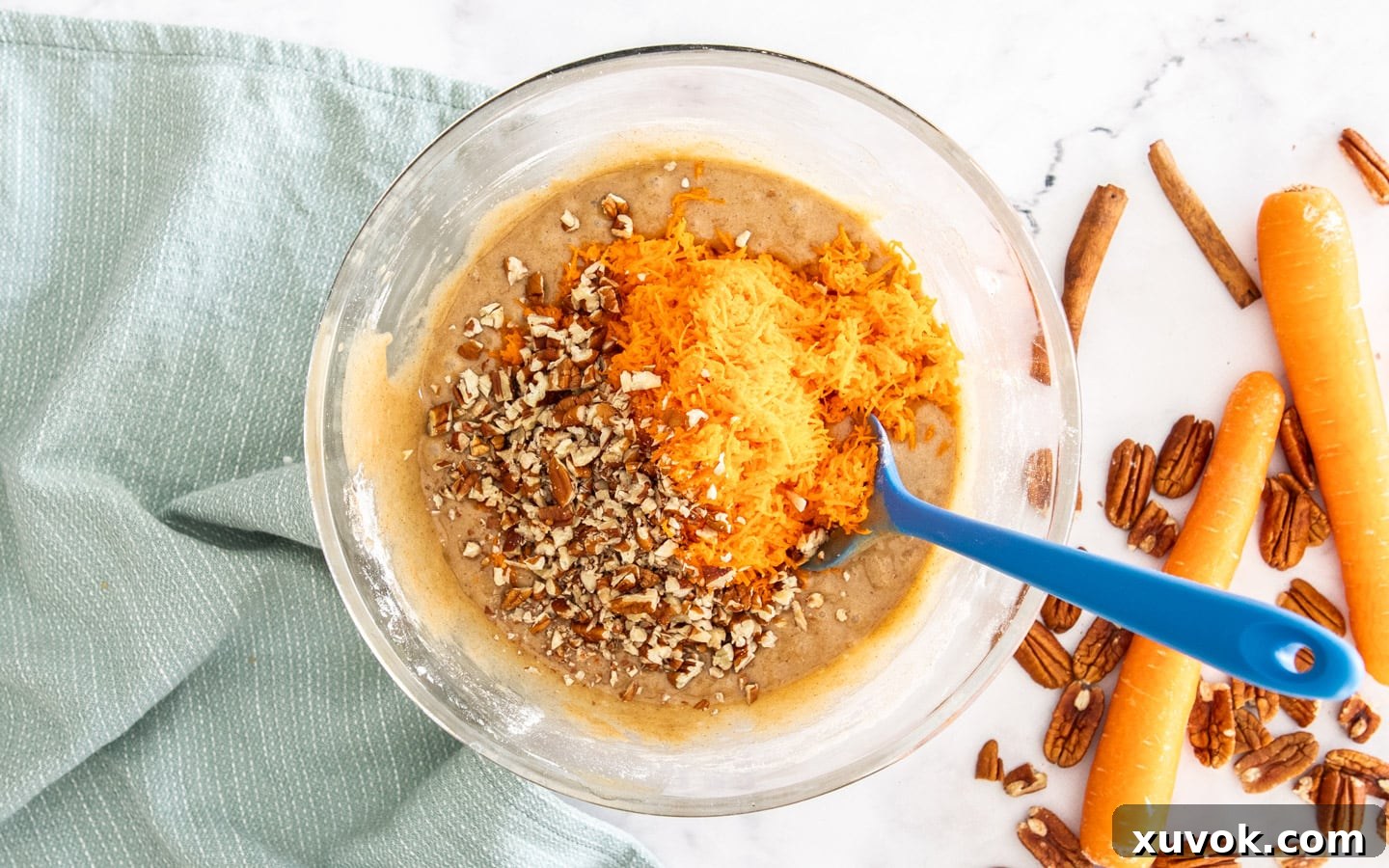 Finely shredded carrots and chopped pecans added to the carrot cake batter, ready for a final gentle stir.