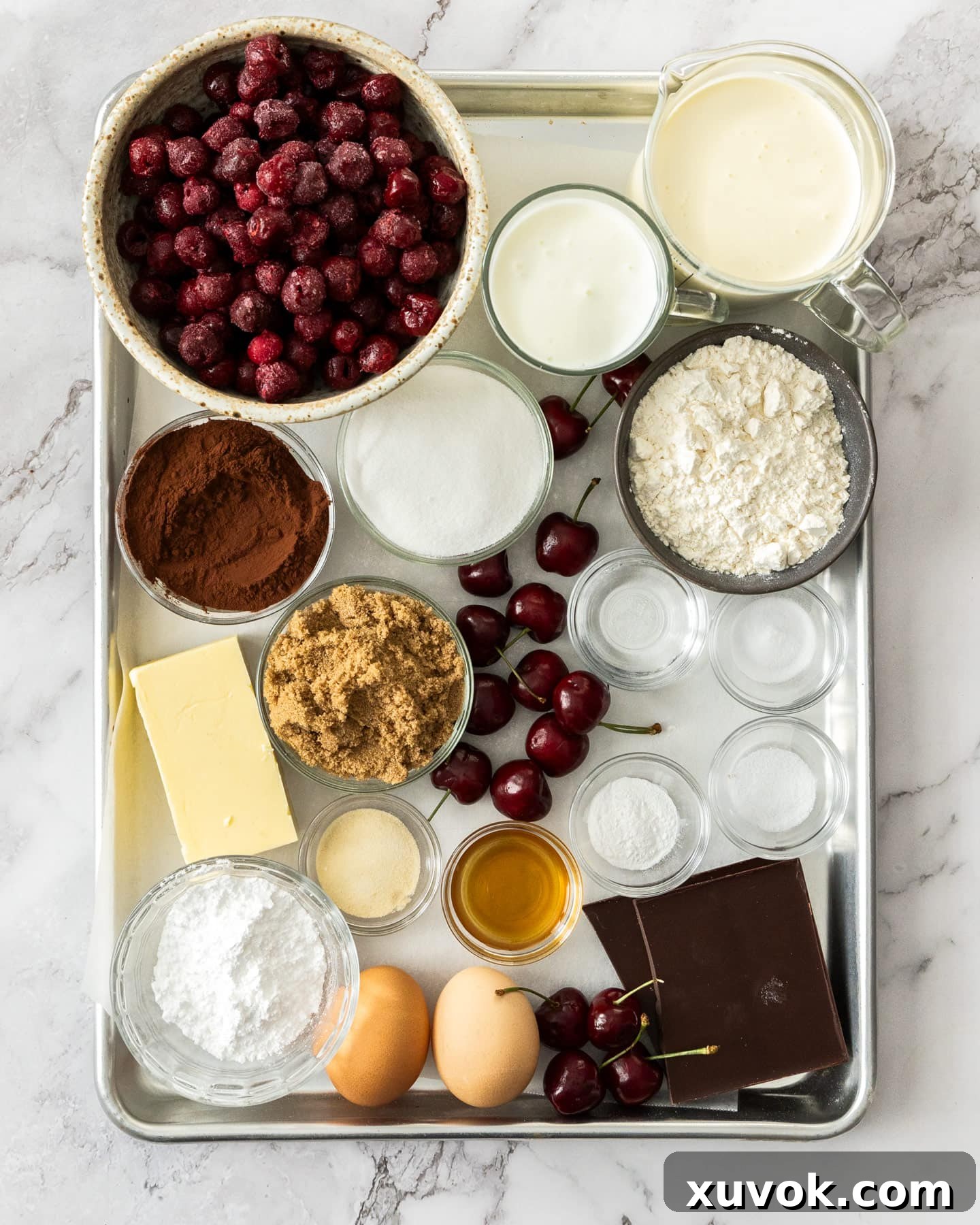 A curated selection of fresh ingredients laid out on a baking sheet, ready for making black forest cupcakes.