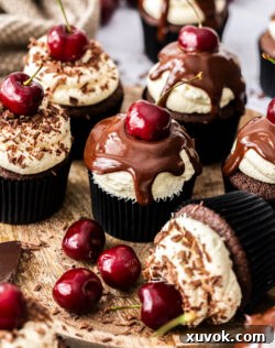 A batch of black forest cupcakes arranged beautifully on a rustic wooden board.