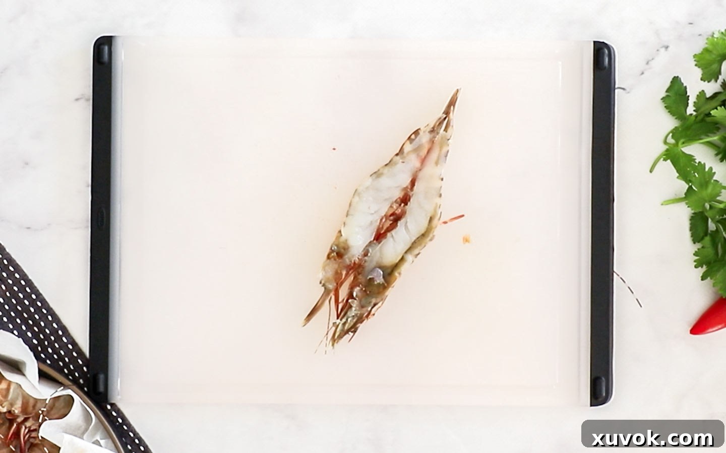 A single perfectly butterflied prawn on a chopping board.