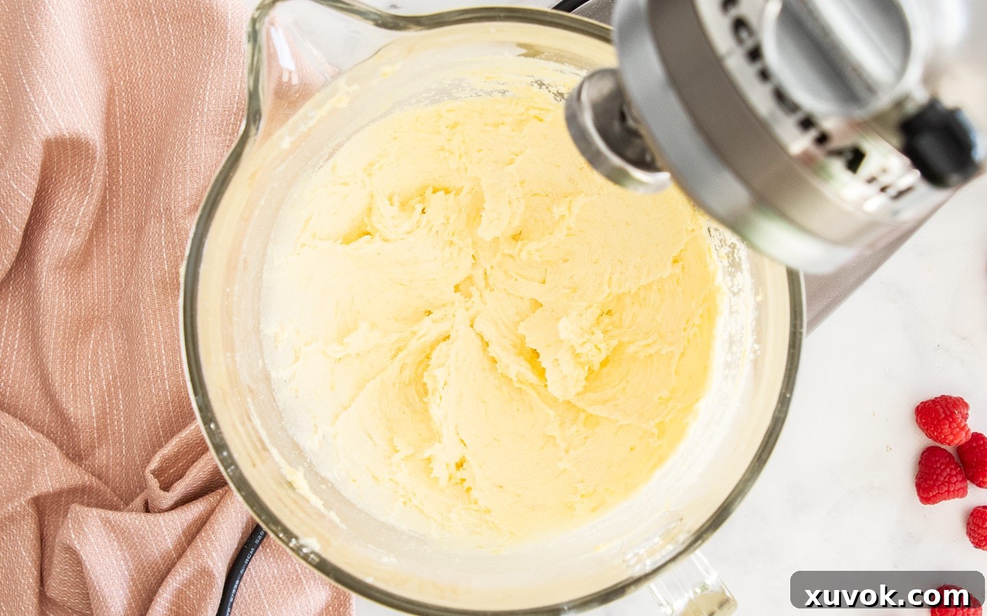 The pale, light, and fluffy creamed butter and lemon sugar mixture in the bowl of a stand mixer, showcasing the successful creaming stage of the cake batter.
