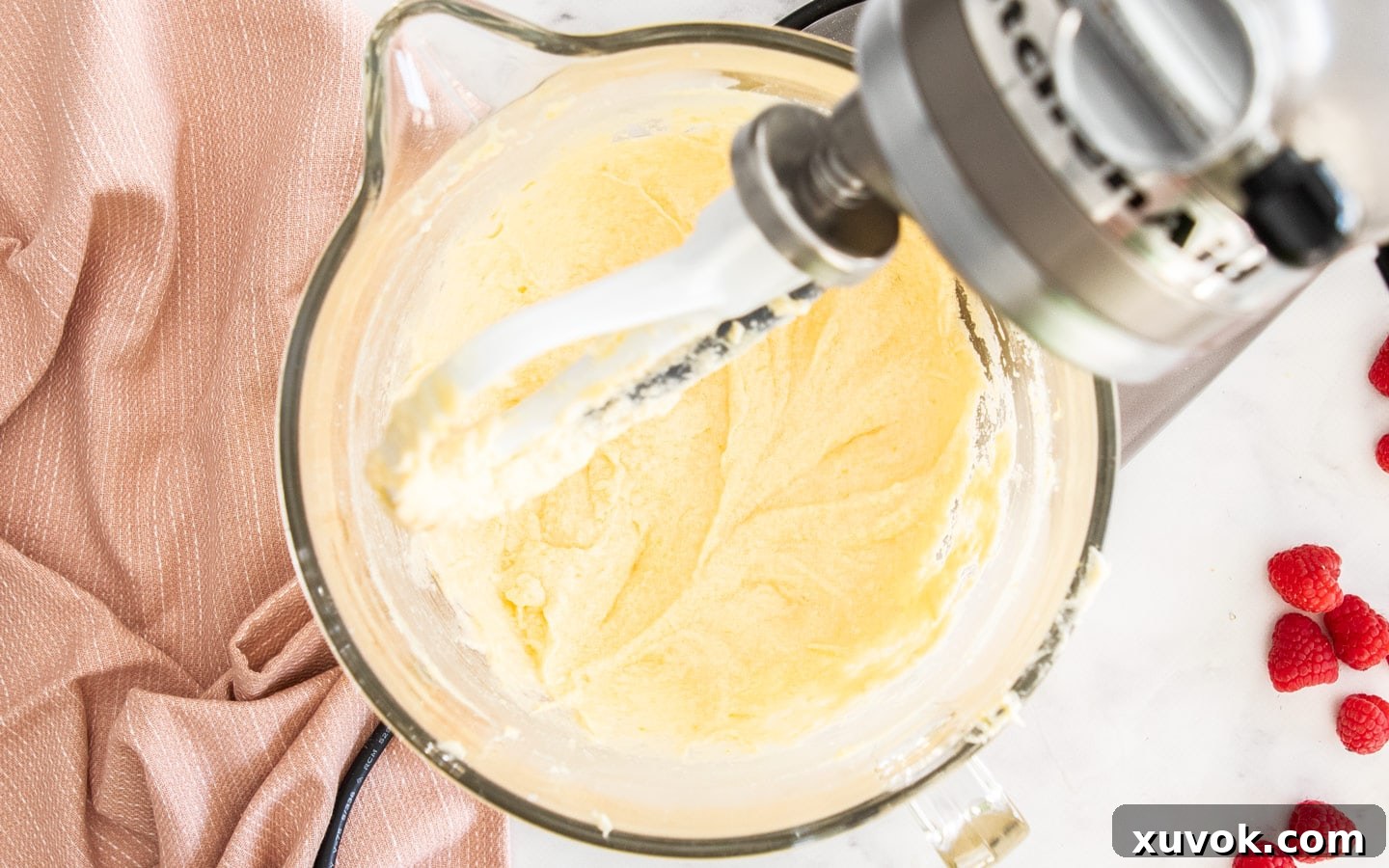 The cake batter in a mixing bowl after the eggs have been thoroughly incorporated, appearing slightly emulsified and smooth, ready for the next additions.