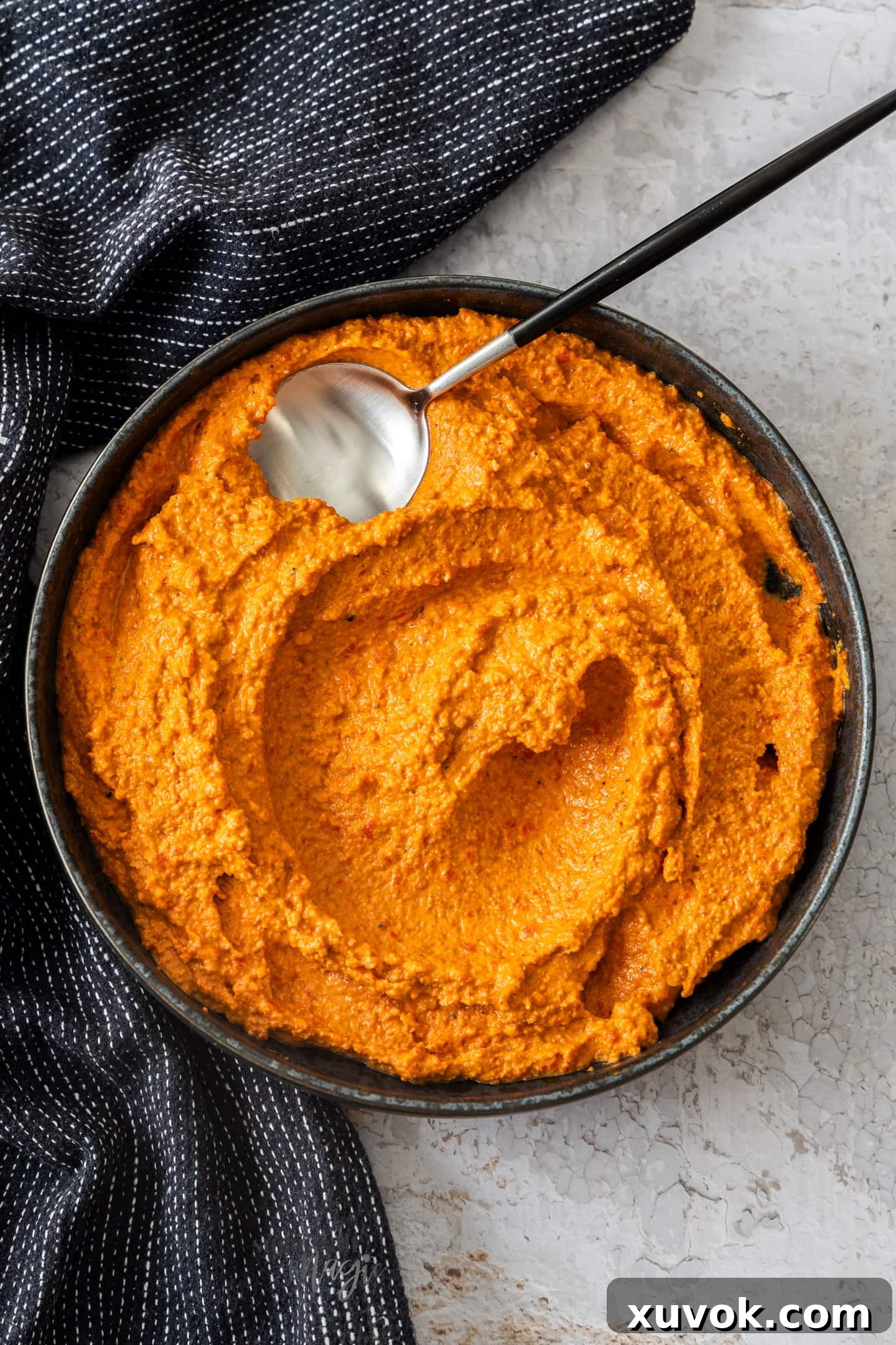 Top down view of romesco sauce swirled in a rustic bowl, showcasing its rich texture and vibrant color.
