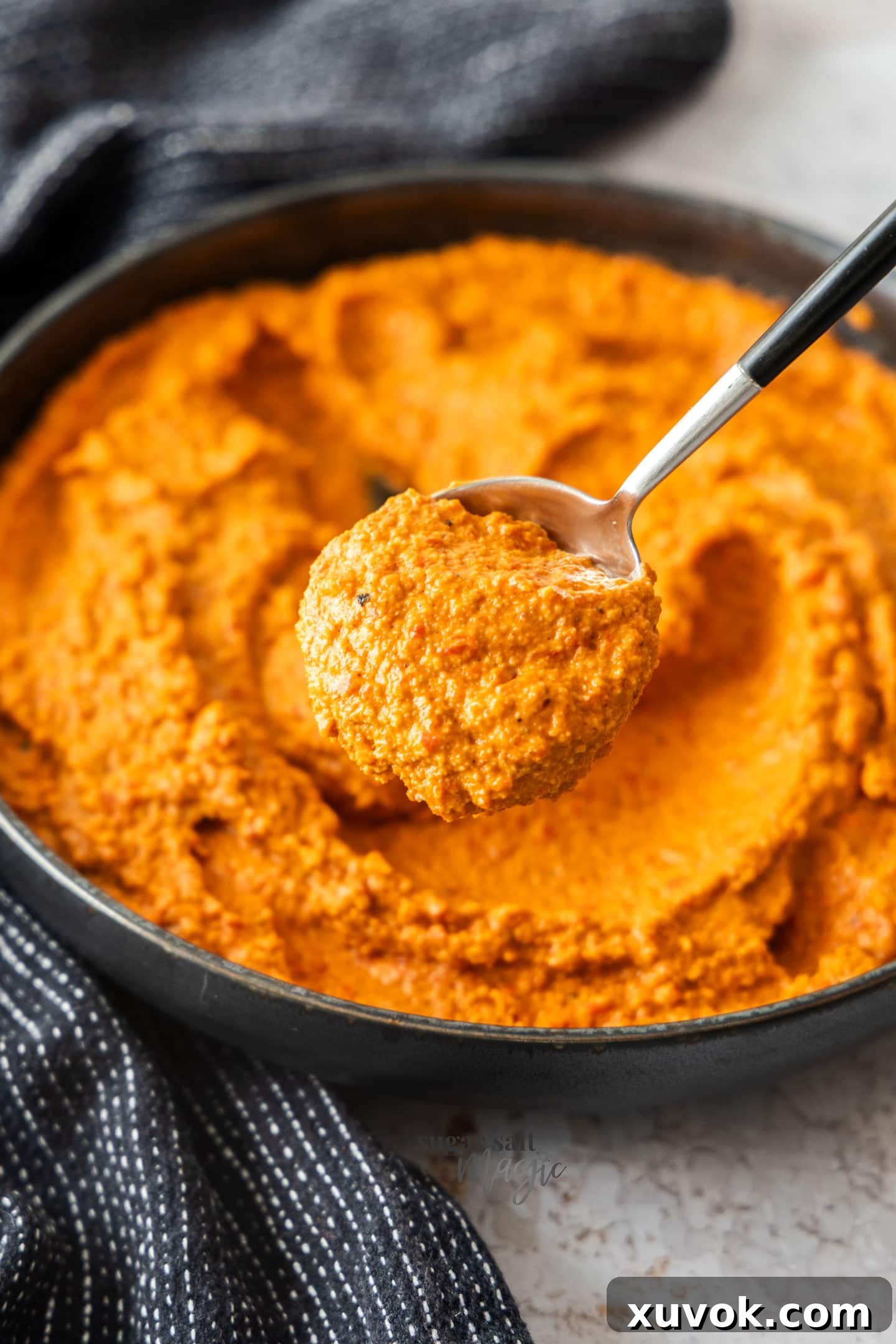 A close-up shot of a spoonful of creamy Romesco sauce, showing its textured consistency and rich color, ready to be enjoyed.