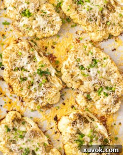 Top down view of 6 cheesy cauliflower steaks on a platter.