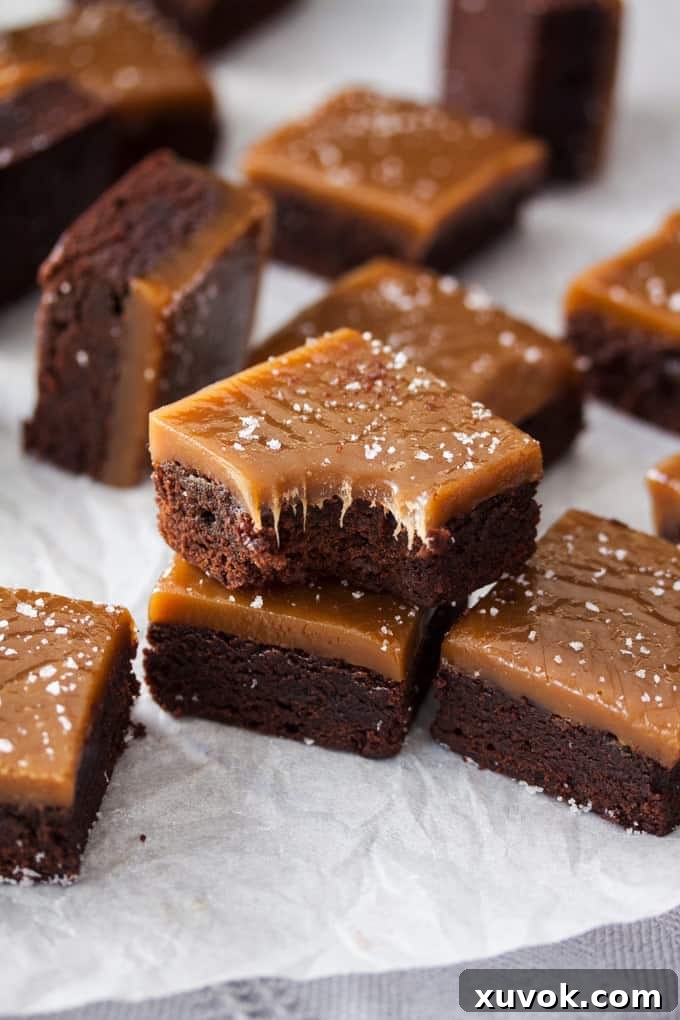 Closeup of a chocolate brownie topped with chewy caramel with a bite taken out of it.