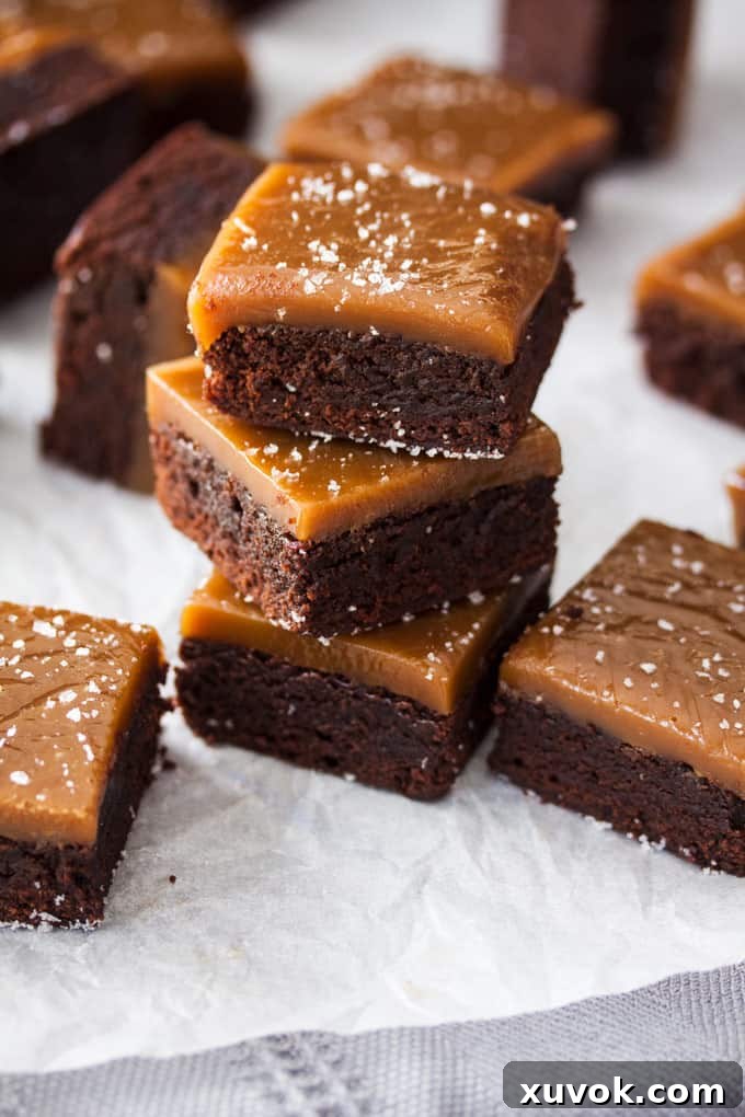 A stack of 3 chocolate brownies with caramel on top.