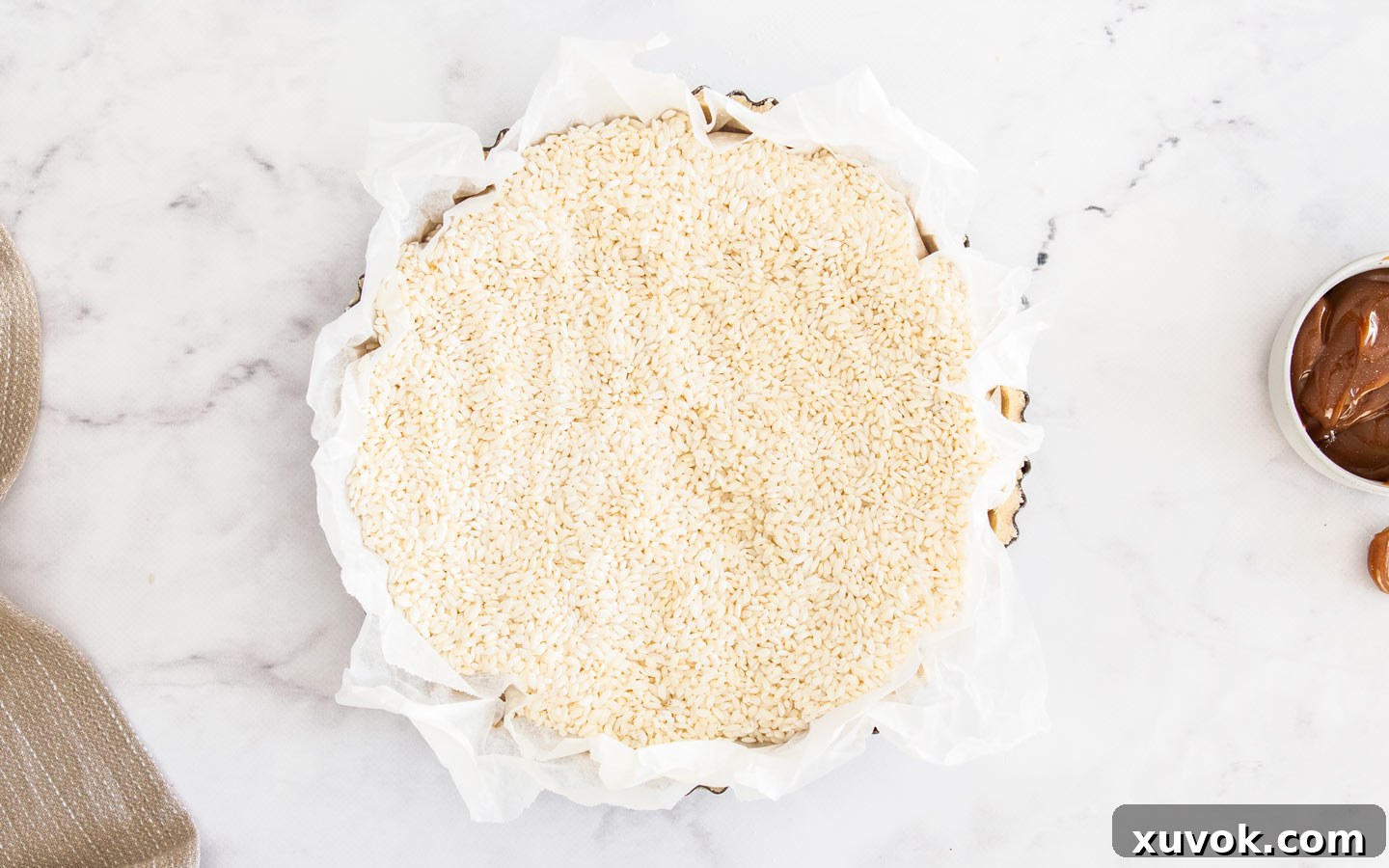 Rice being used as pie weights in paper inside the tart shell during blind baking.