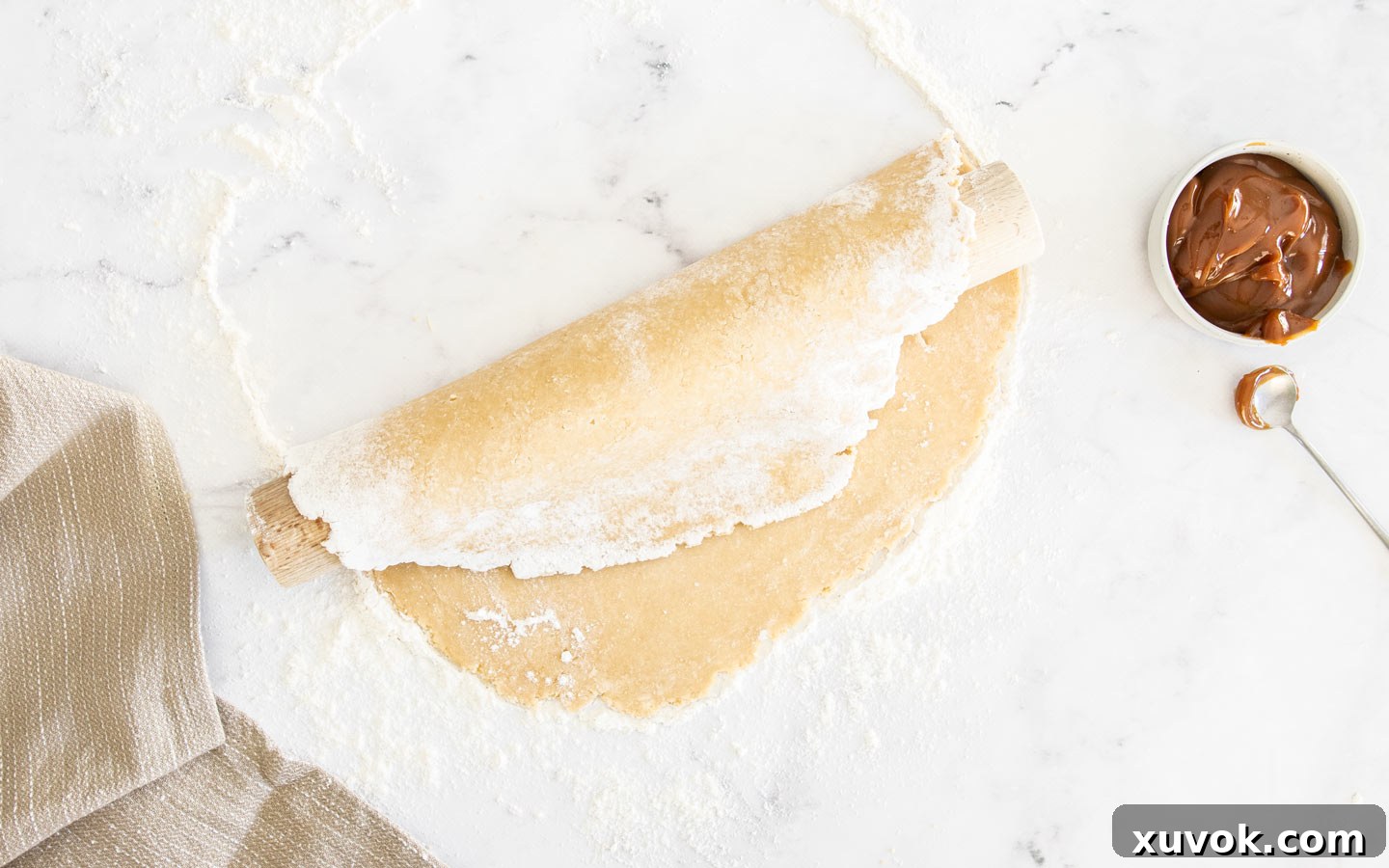 Pastry dough carefully folded over a rolling pin, demonstrating the transfer technique.