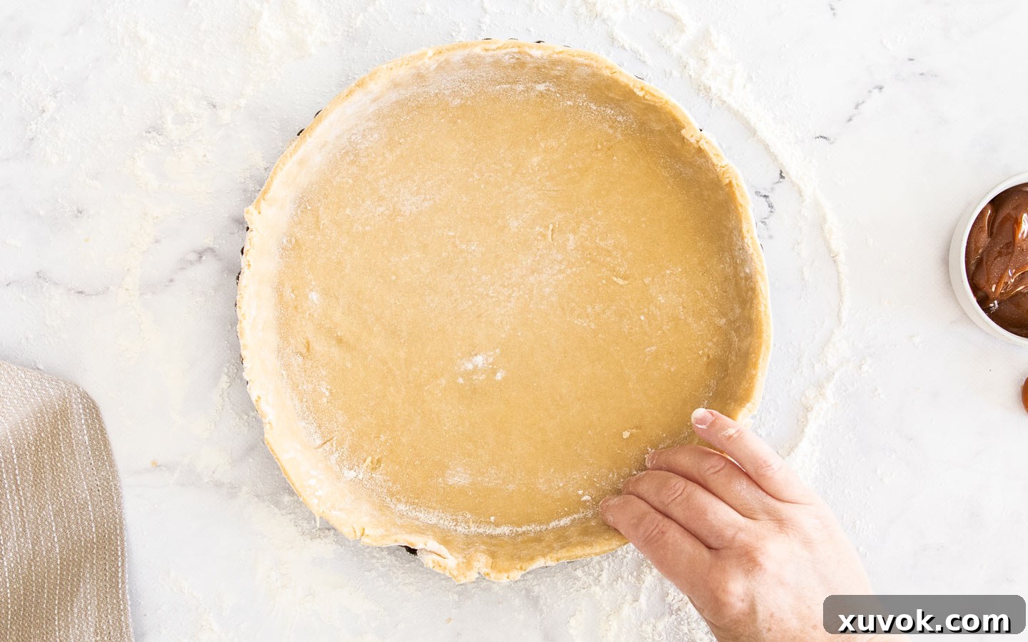 Pressing the pastry dough into the tart pan, ensuring it fits snugly into the fluted edges.