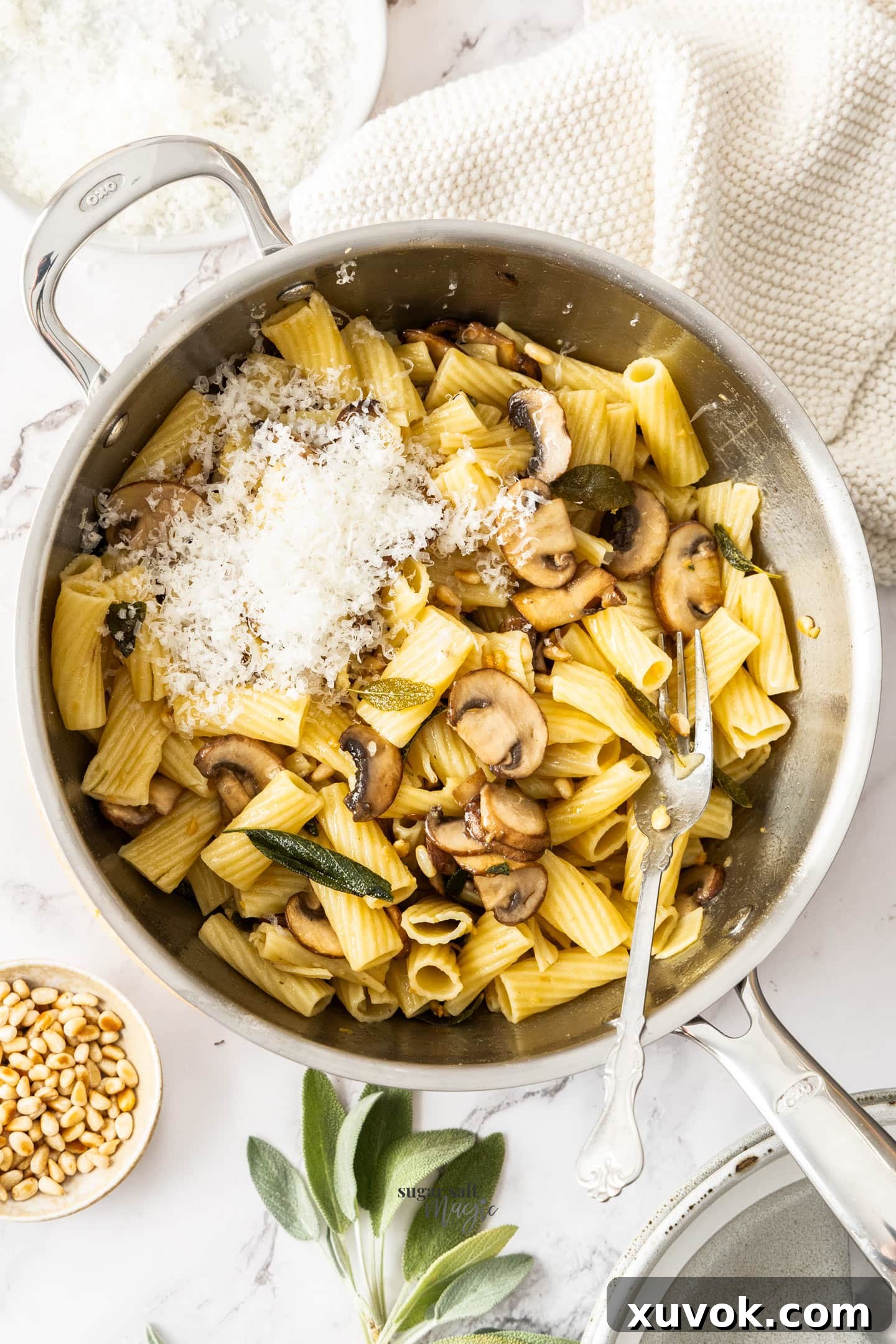 A large pan filled with freshly made sage butter pasta, generously topped with grated Parmesan cheese, ready to be served.