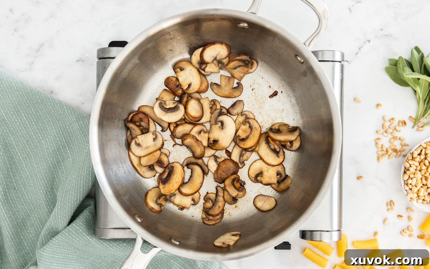 Thinly sliced mushrooms being sautéed in a pan with a glossy sheen, indicating they are cooking down to a golden-brown crisp.