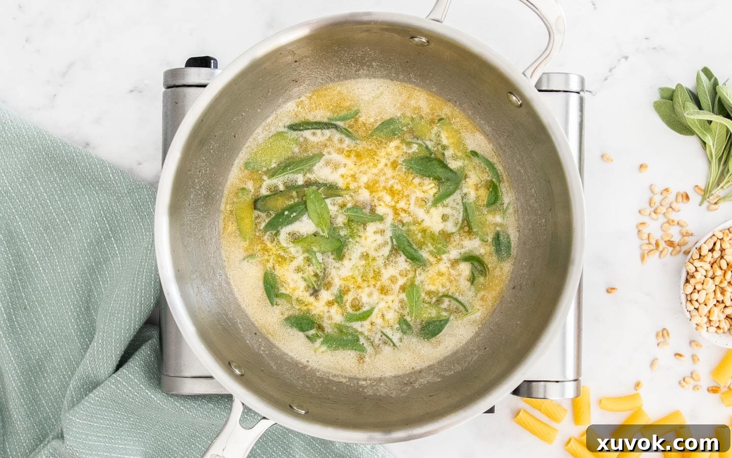 Bright green fresh sage leaves and finely minced garlic being stirred into sizzling, foaming butter in a pan.