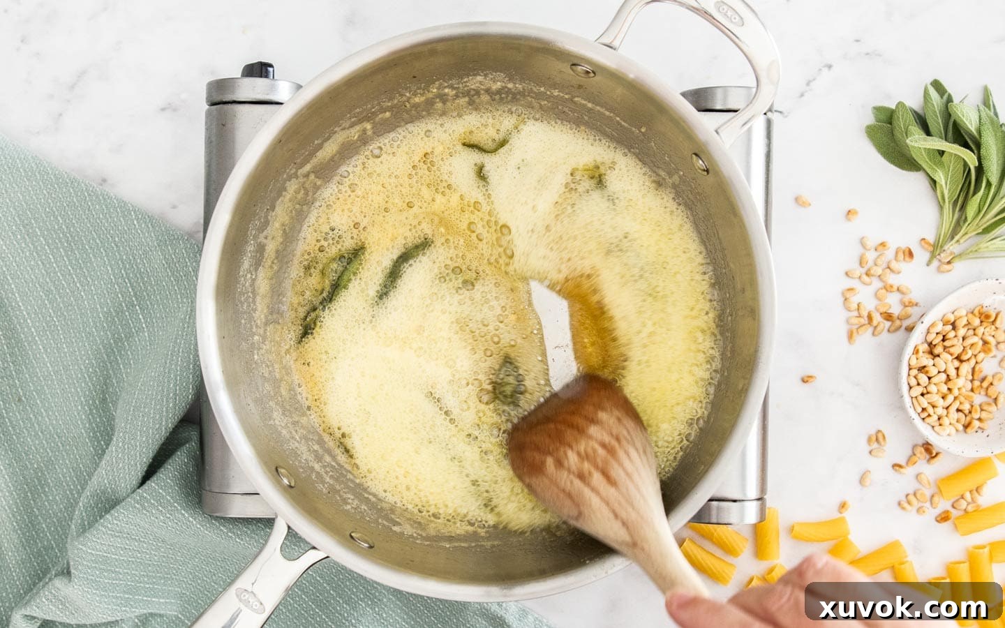 Golden-amber brown butter foaming in a pan, with tiny toasted milk solids visible at the bottom, indicating perfect browning.