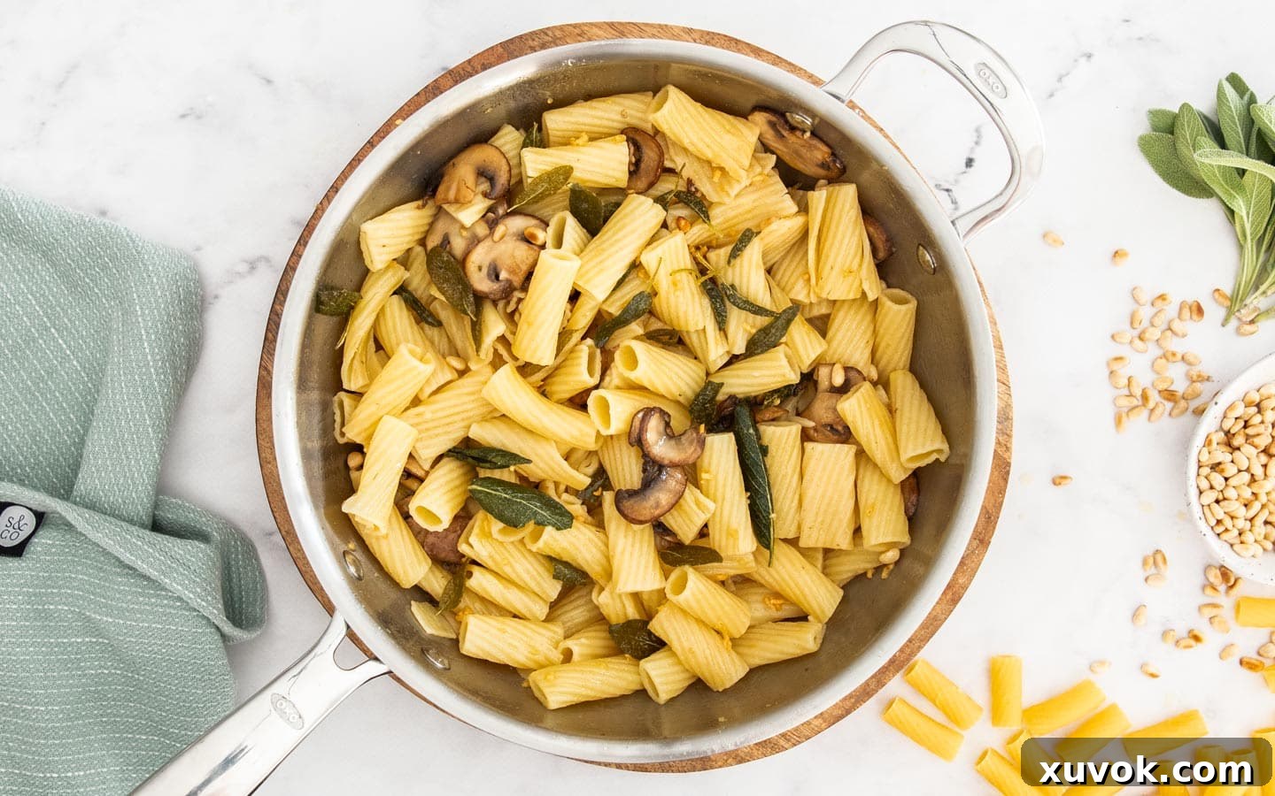 The finished sage butter pasta with mushrooms and pine nuts, beautifully tossed and coated in a rich brown butter sauce, displayed in a pan.