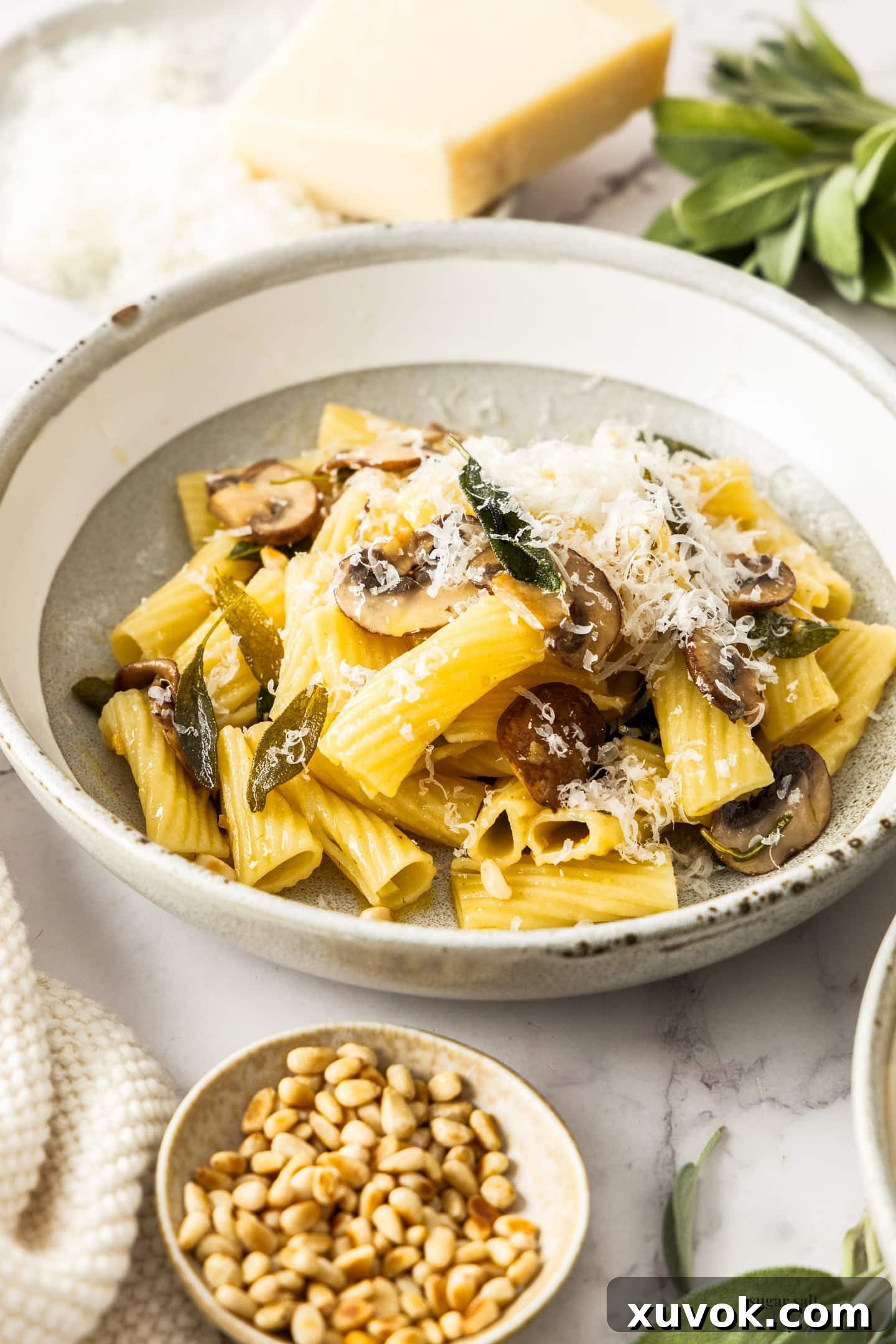 A close-up of a beautifully plated bowl of sage butter pasta, adorned with a generous sprinkle of finely grated Parmesan cheese, ready for enjoyment.