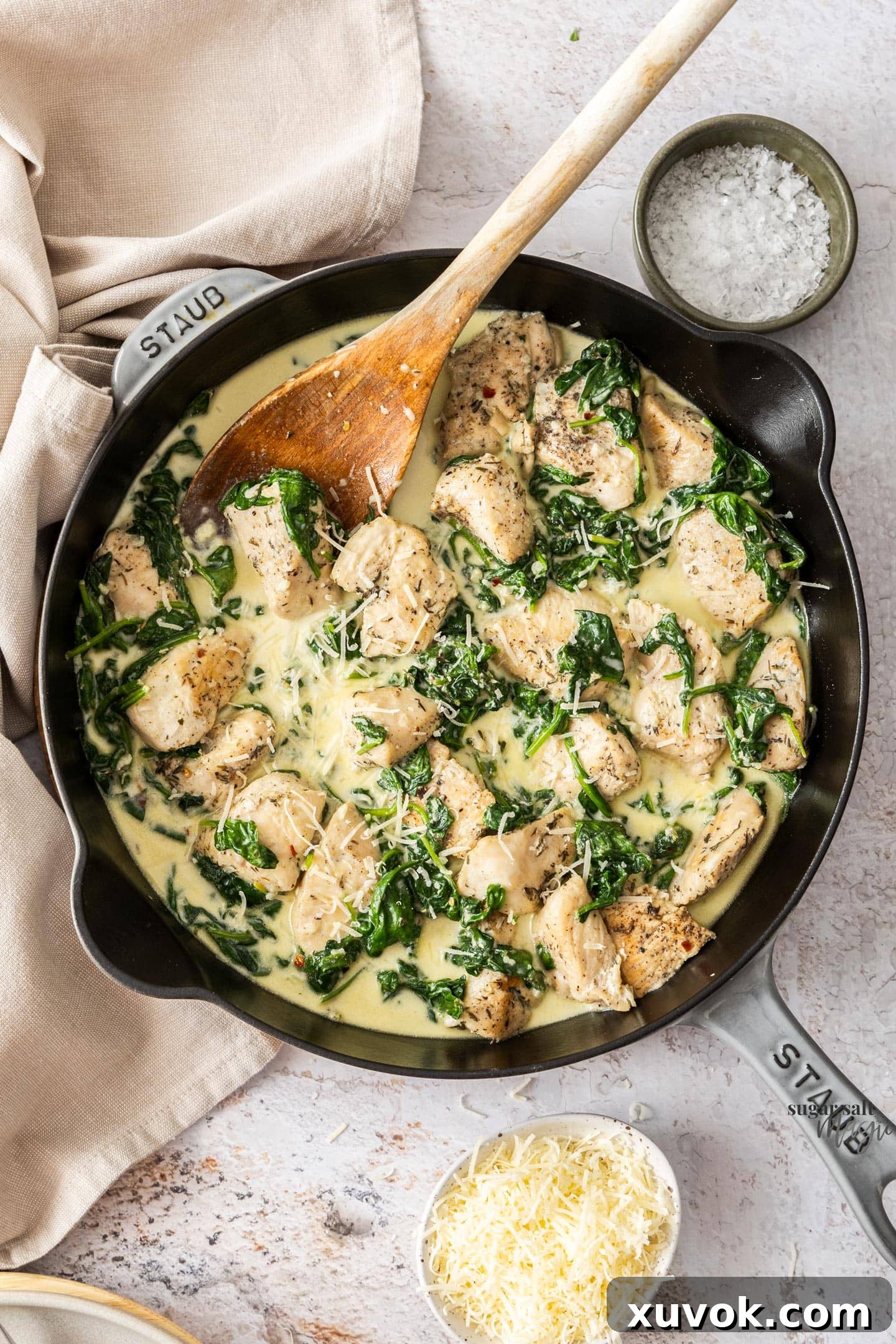 A skillet filled with cooked chicken and spinach in a creamy sauce.