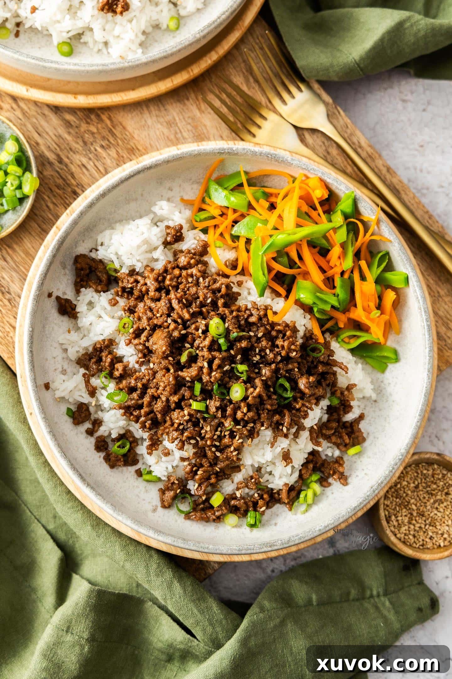 Top down view of a bowl of rice topped with teriyaki beef mince and veggies.